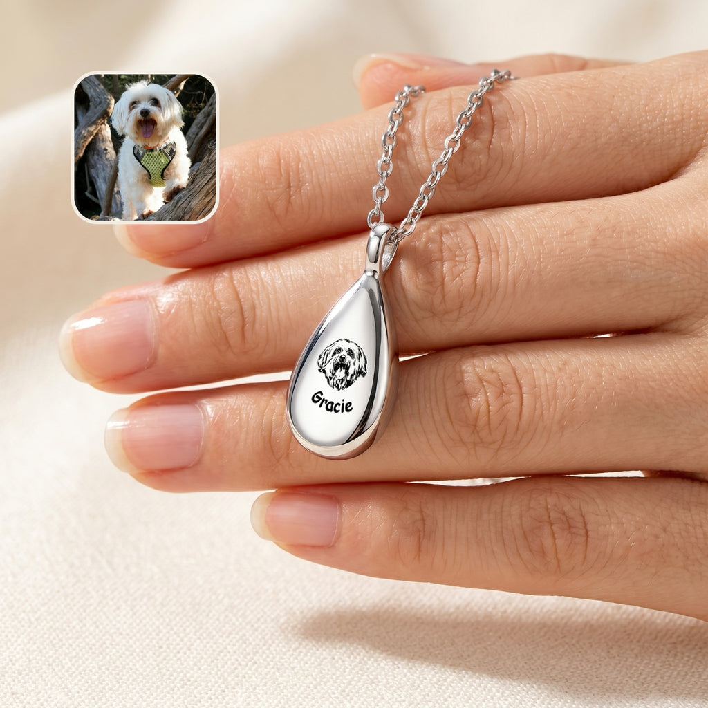 Silver teardrop pet photo urn necklace with hand-drawn dog portrait and name engraving, held in hand