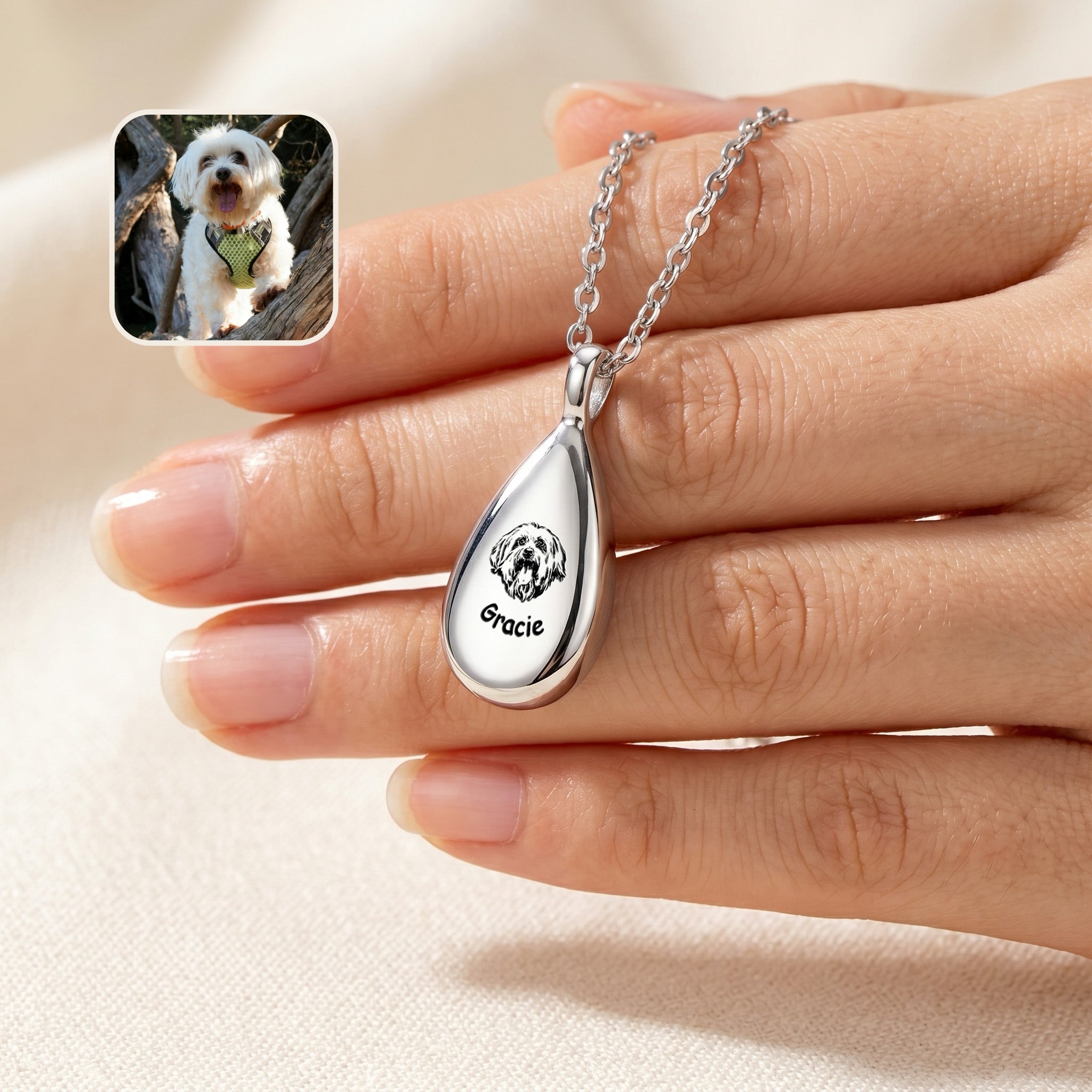 Silver teardrop pet photo urn necklace with hand-drawn dog portrait and name engraving, held in hand