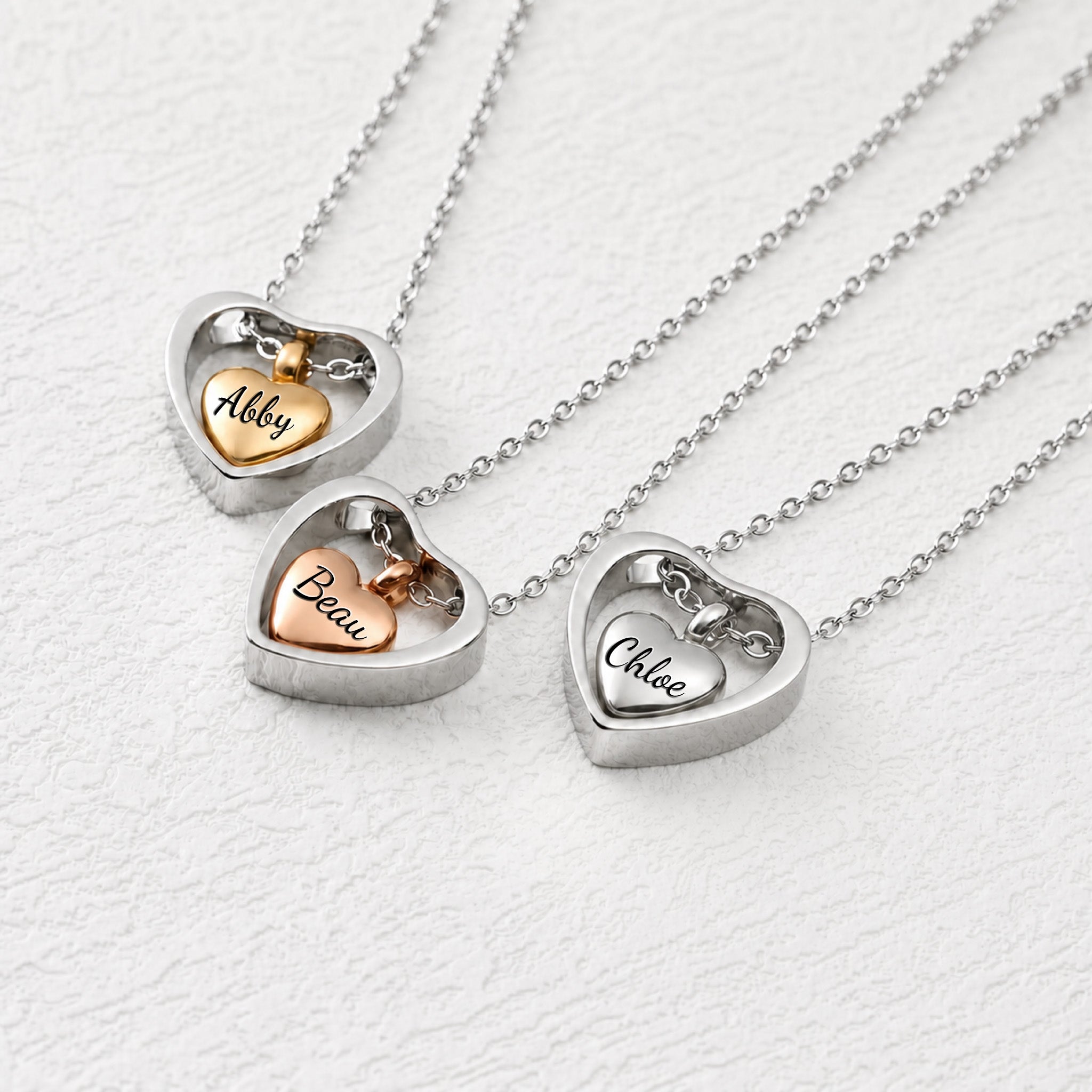 Heart urn necklace for pet ashes in three finishes — rhodium, 18k gold, and 18k rose gold inner hearts inside open heart frames