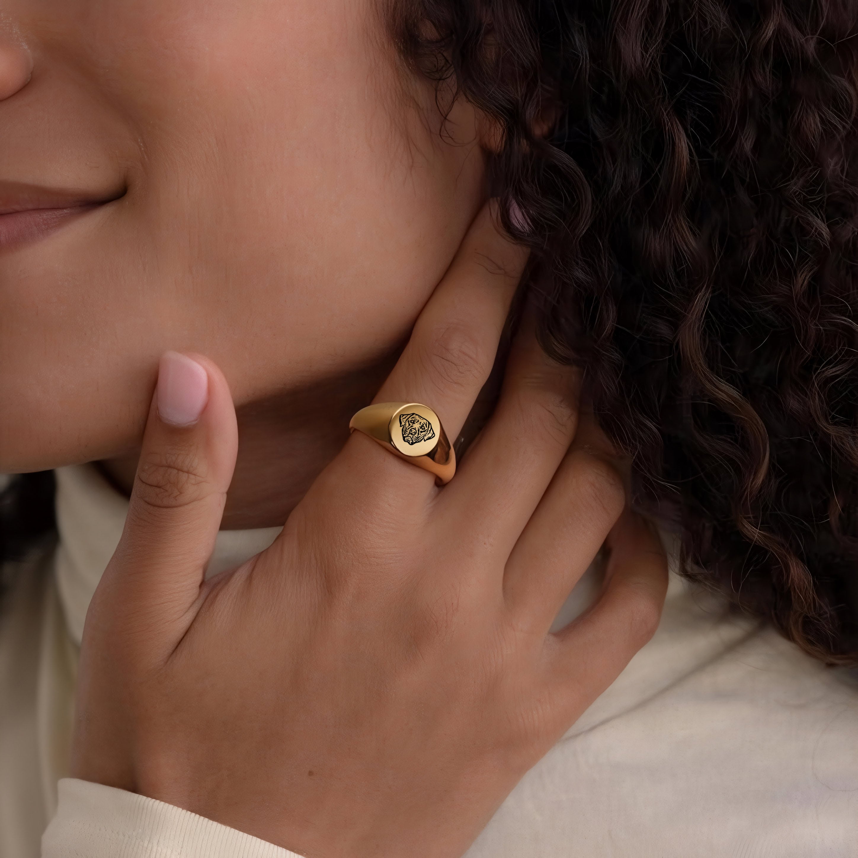 Hand wearing a gold pet face ring with engraved portrait, lifestyle close-up near the face