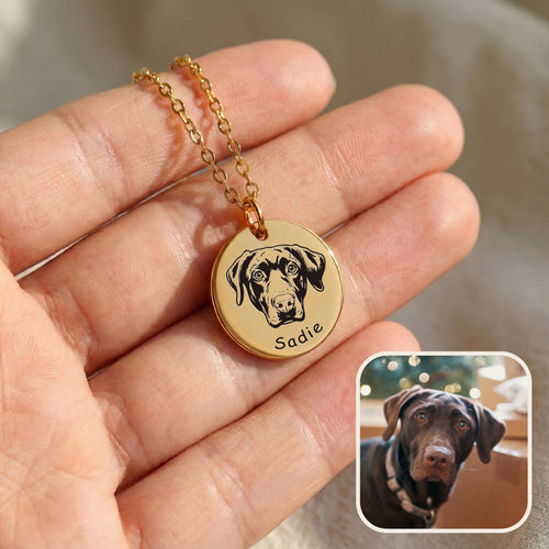 Hand holding gold pet face necklace with hand-drawn dog portrait engraving and inset pet photo