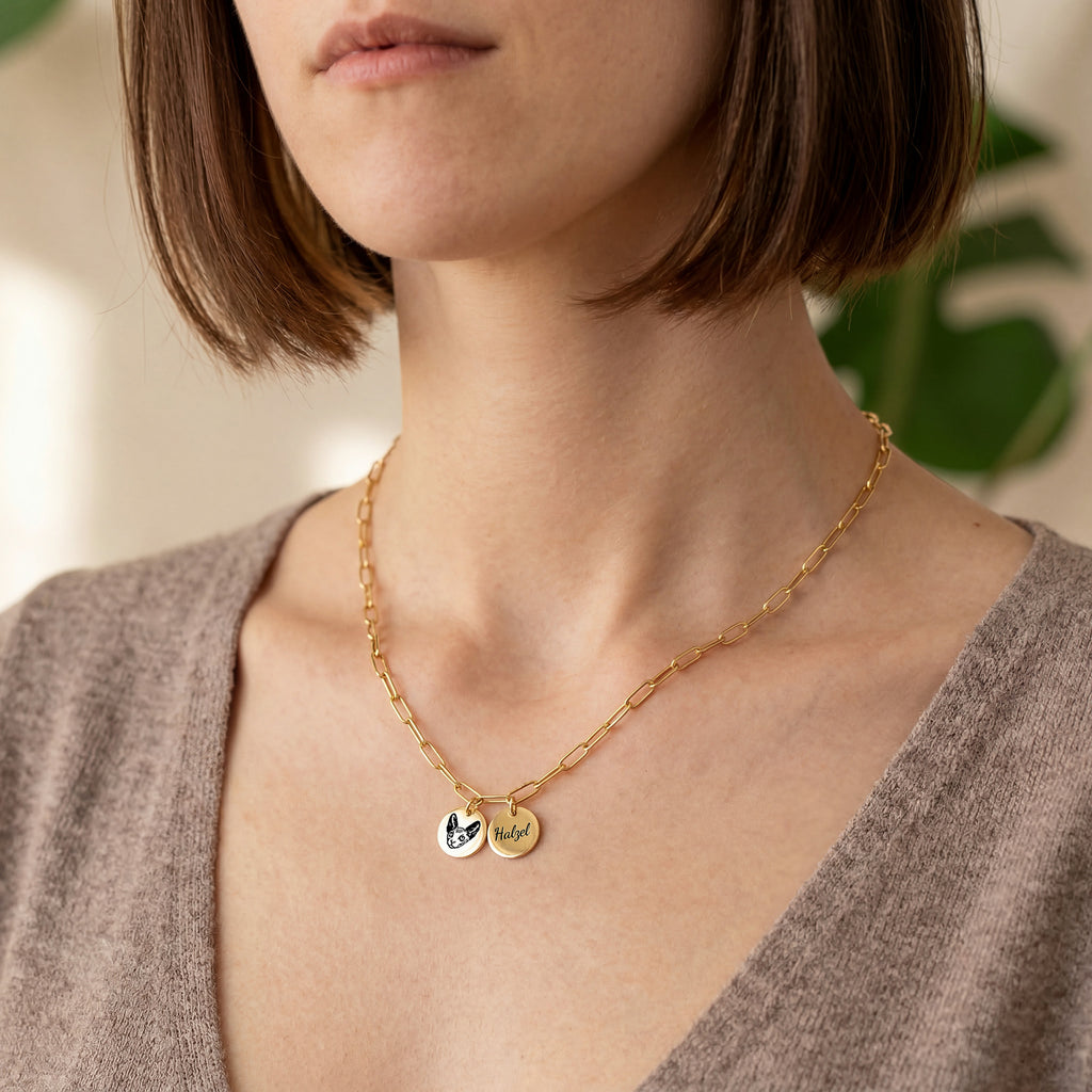 Woman wearing gold paperclip chain necklace with pet portrait and name disc pendants, lifestyle view