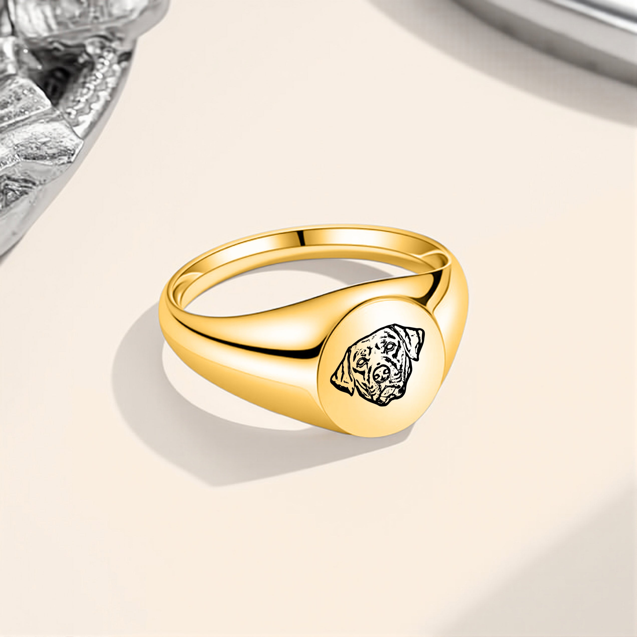 Gold pet portrait signet ring with laser-engraved portrait displayed on a beige surface