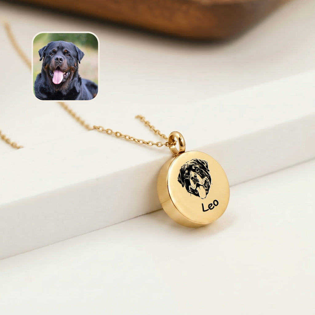 Close-up of 18K gold pet photo urn pendant with hand-drawn rottweiler portrait and name engraving, resting on white surface