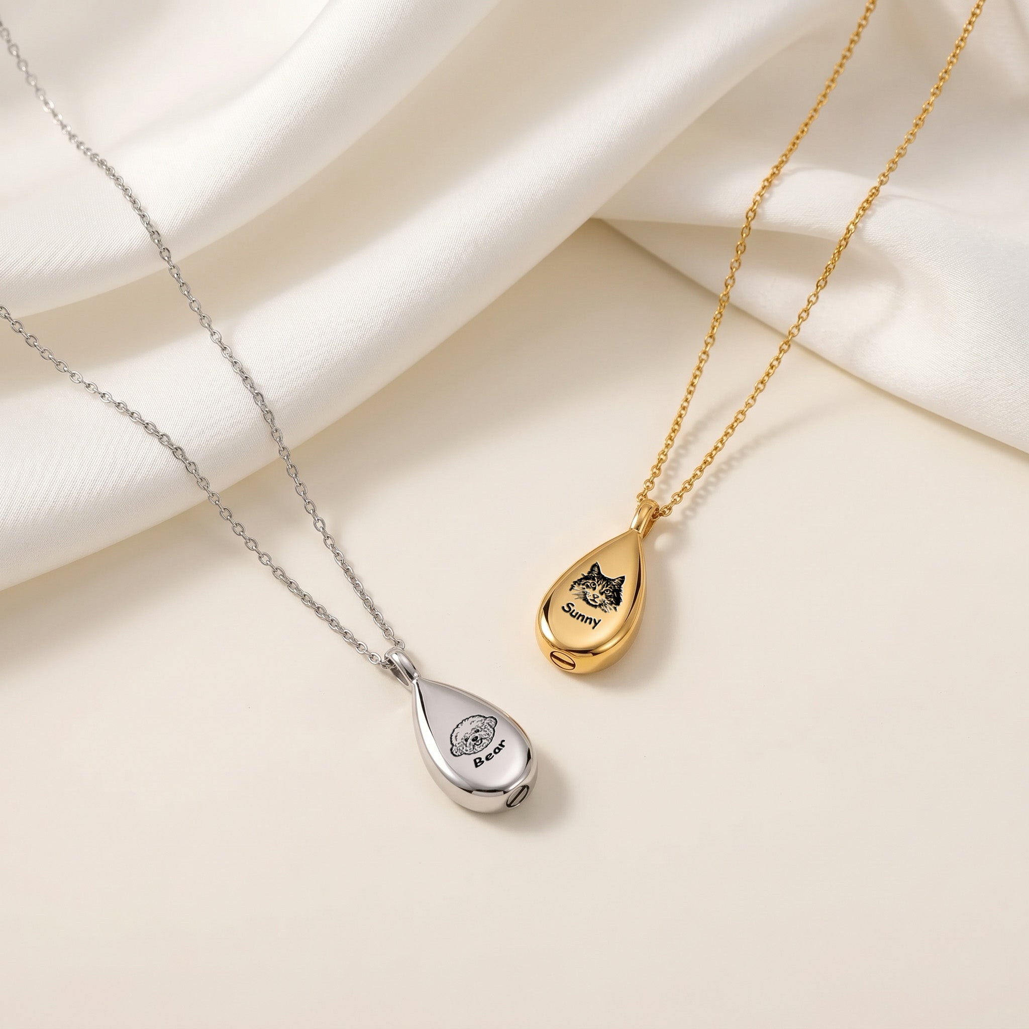 Silver and gold teardrop pet photo urn necklaces with cat and dog portraits on cream satin fabric