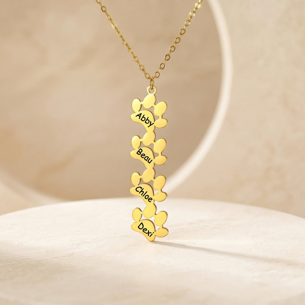 Four gold paw pendants with names Abby Beau Chloe Dexi on cream stand