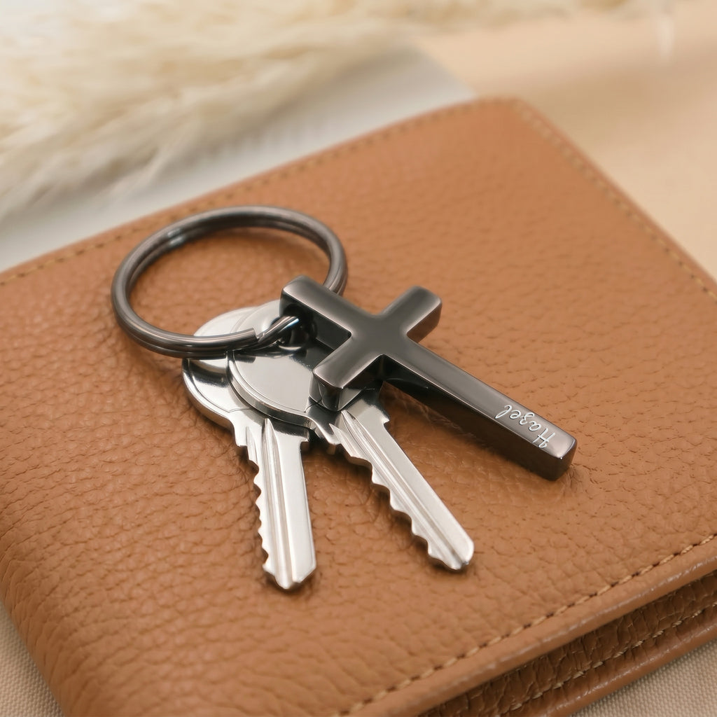 Matte black pet cross keychain staged with keys and a brown wallet — everyday-carry pocket scene; the new fourth finish for PupTrace keychains