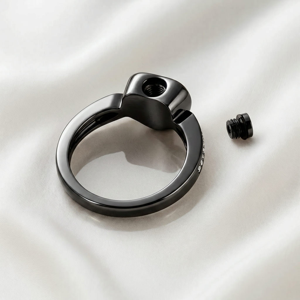 Back of black heart urn ring showing threaded fill hole with screw removed, ashes chamber visible