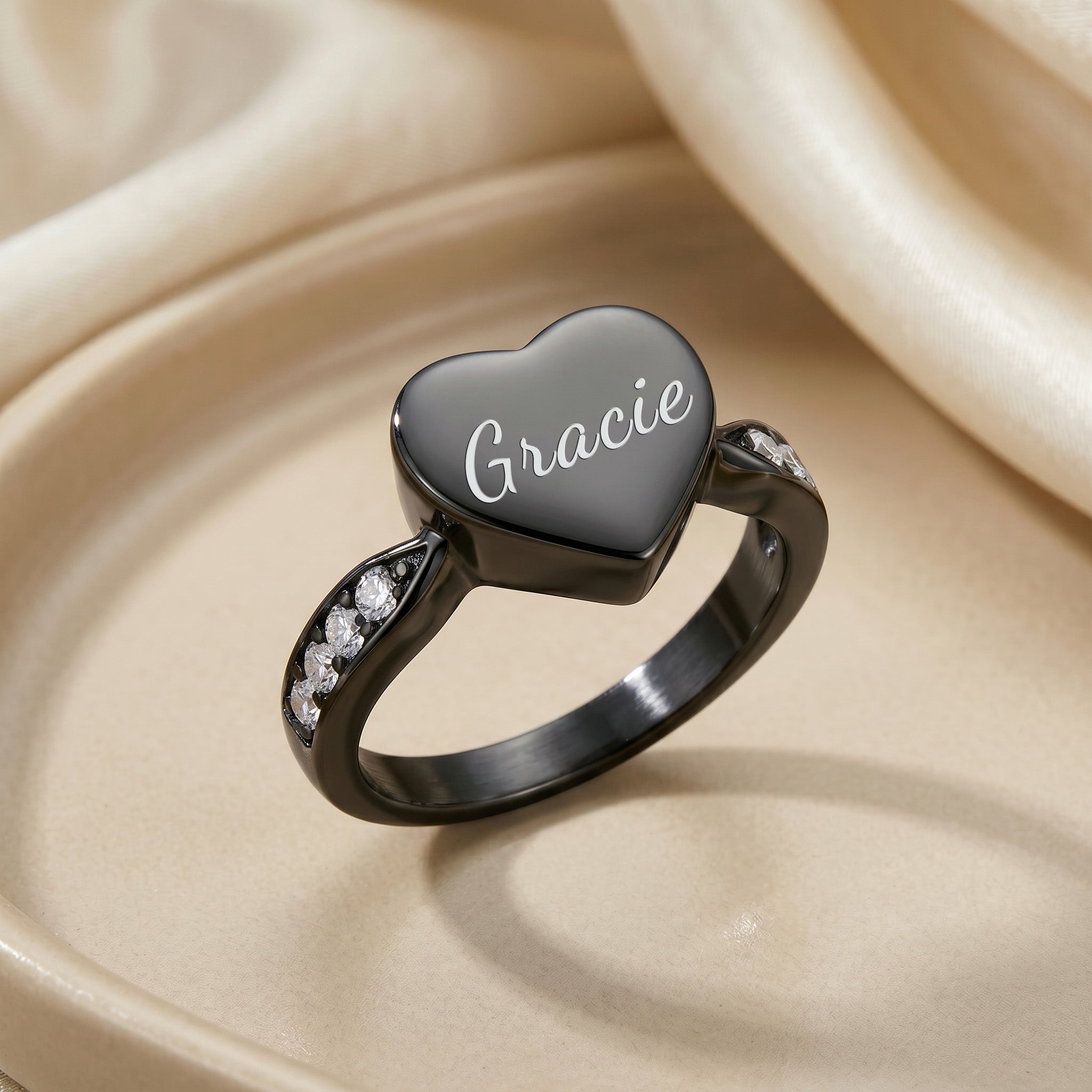 Black heart urn ring on satin fabric, angled to show heart contour and band profile