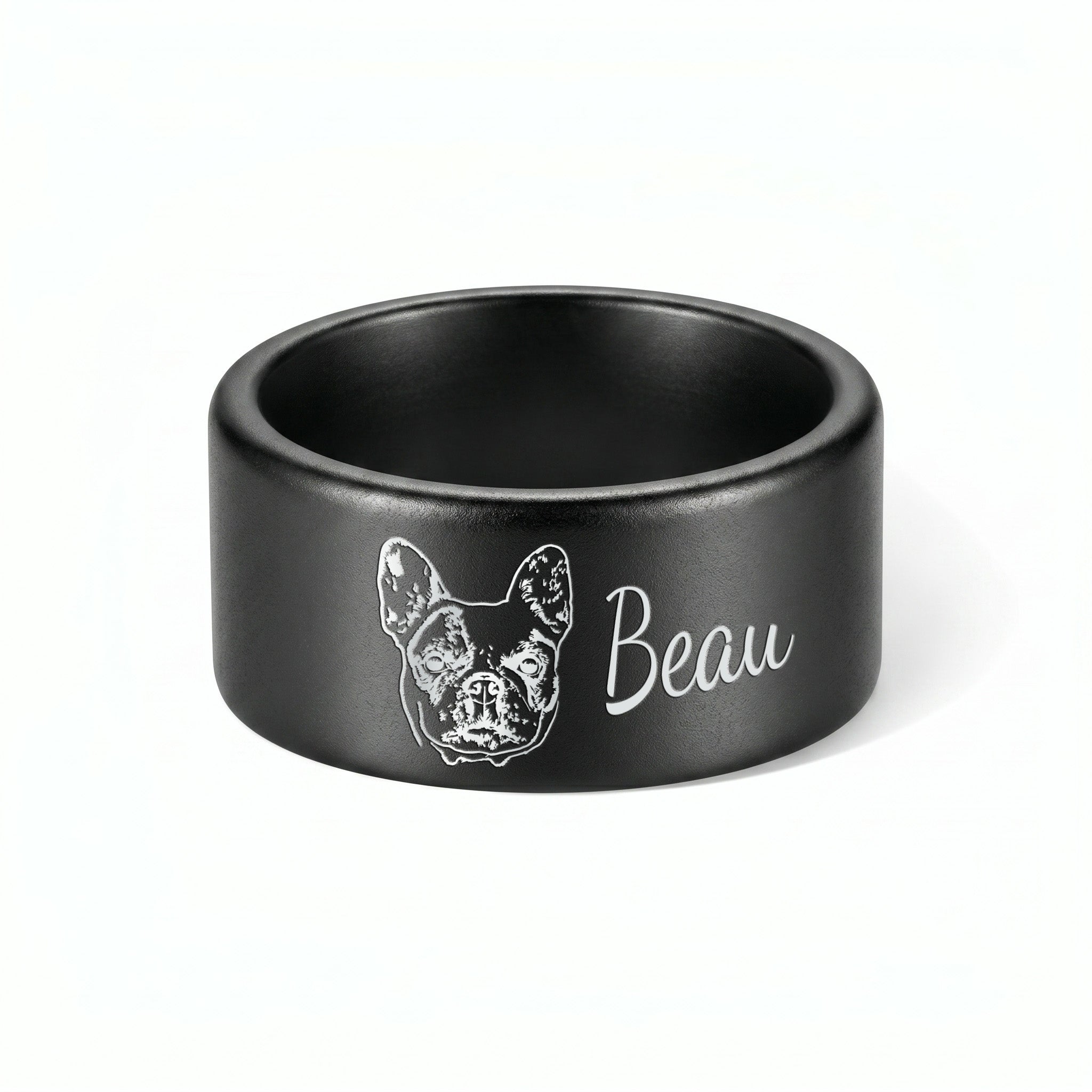 Single matte black wide band pet ring on a near-white background, engraved portrait and script name