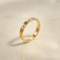 Gold dog name ring with a pet’s name and a paw laser-engraved on a slim band, angled on a cream stone tray