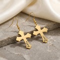 18K gold pet cross earrings shown as a matched pair on a gray stone slab — pet name laser-engraved in script on the lower stem of each cross