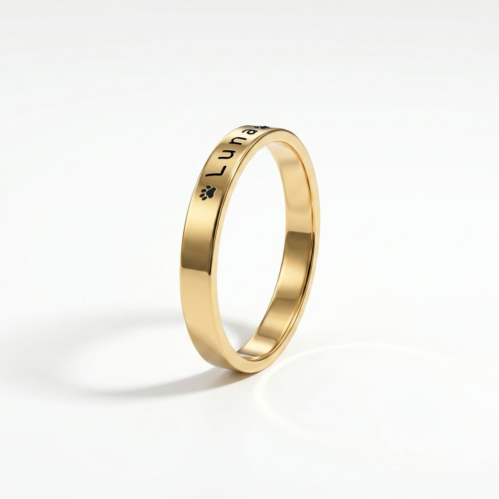 Gold pet name band ring on a near-white background with a soft shadow