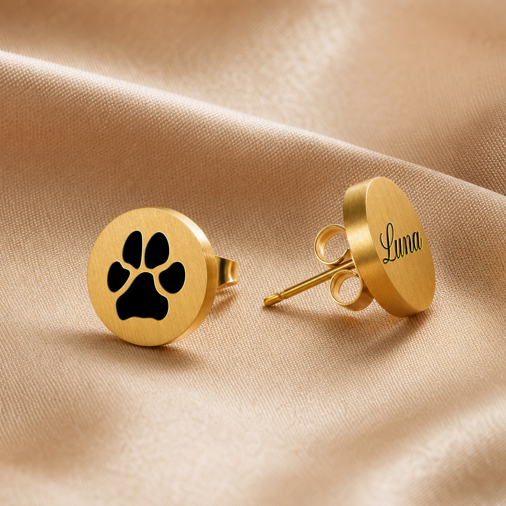 Gold pet name stud earring with script-engraved pet name on a round disc, staged on champagne satin