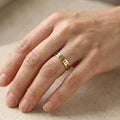 18K gold-plated pet name stacking ring worn on a finger, engraved with a pet's name and paw prints in natural light
