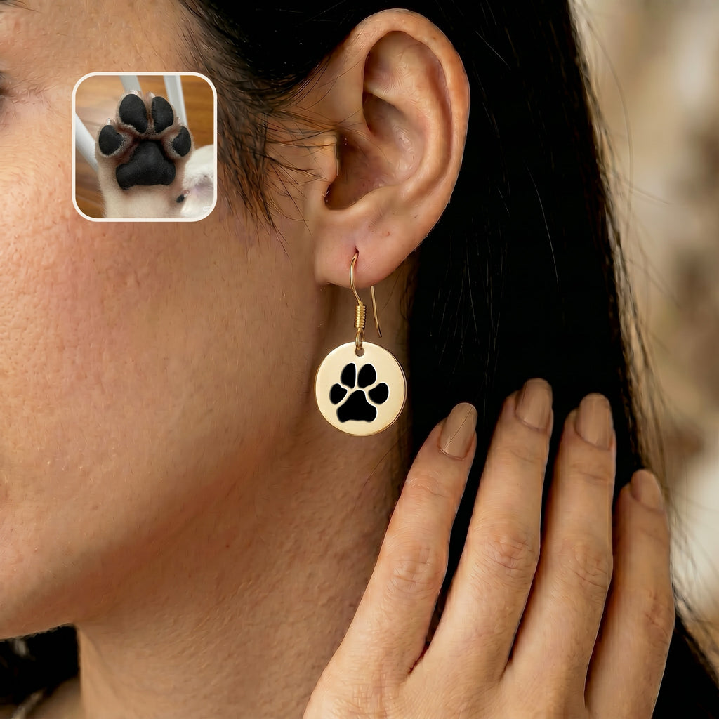 Single gold drop earring worn on one ear, beside an inset photo of a pet's paw
