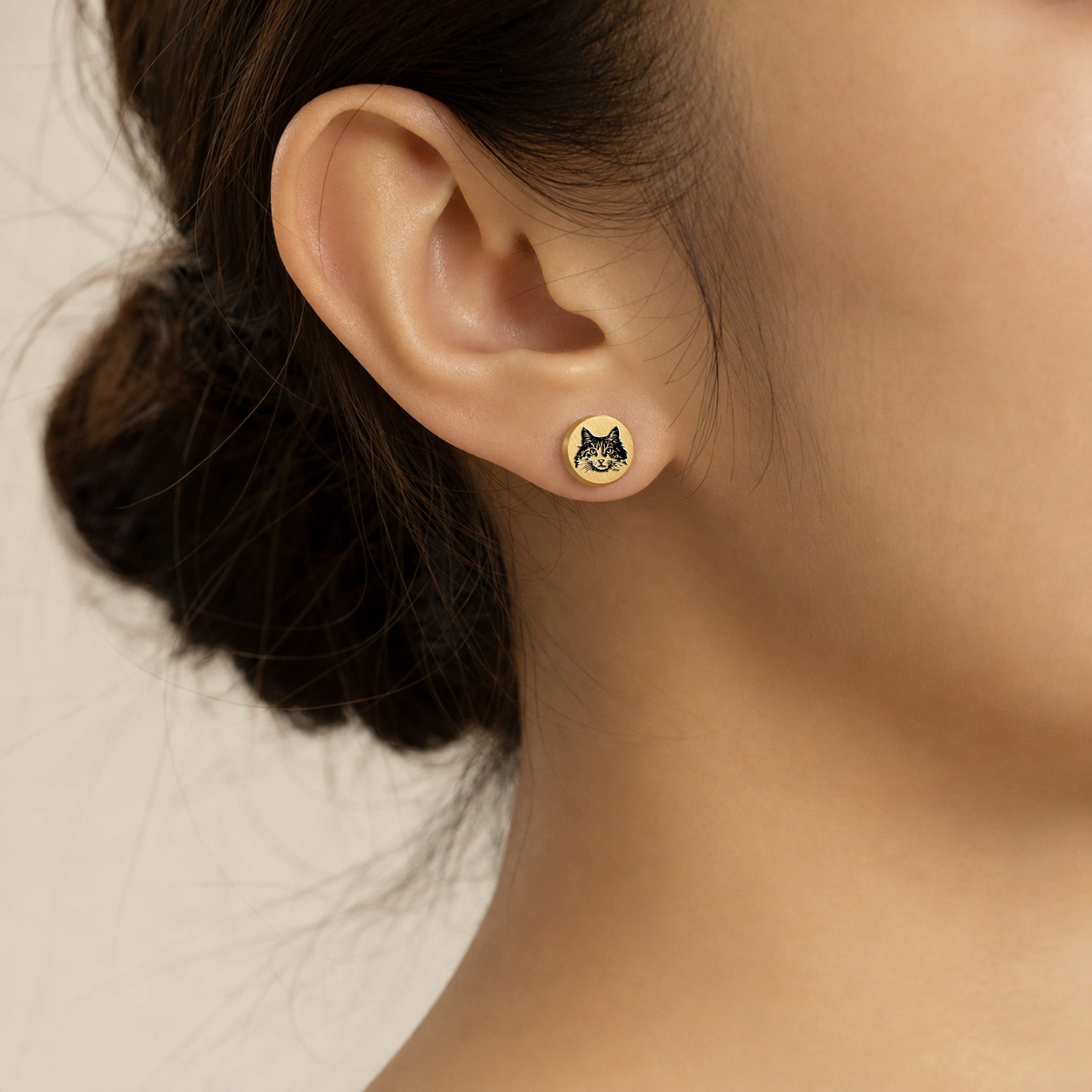 Model wearing a single gold pet portrait stud earring with hand-drawn pet portrait engraving on the earlobe