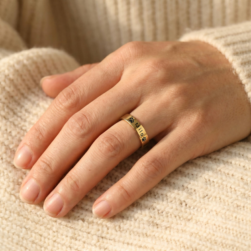 18K gold-plated pet name stacking ring worn on a hand resting on a cream knit sweater