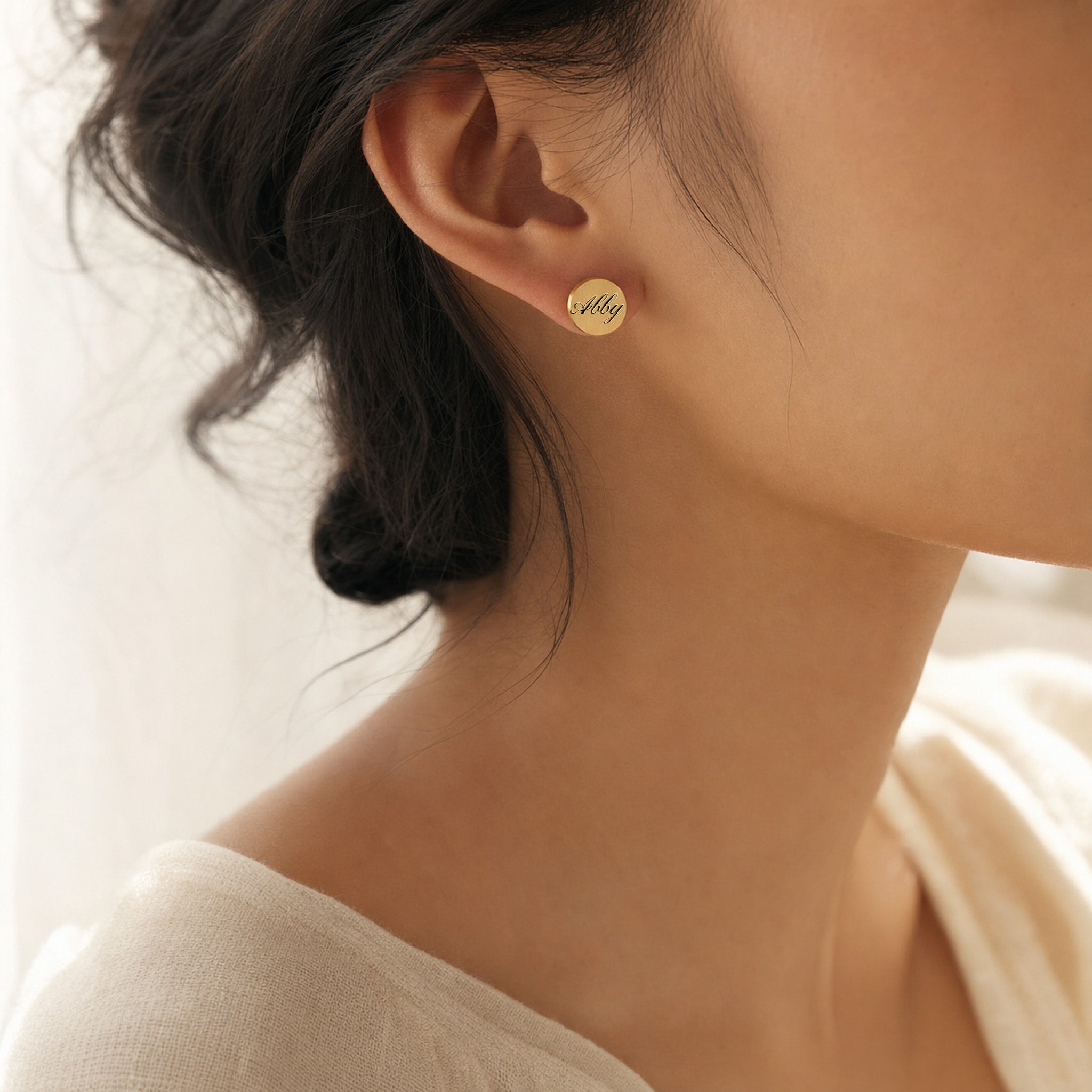 Model wearing a single gold pet name stud earring with script-engraved name, close ear view