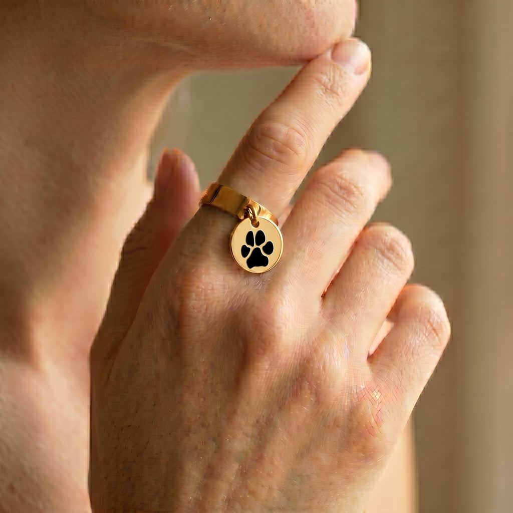 Yellow-gold disc-charm ring worn on a hand in a soft, warm indoor close-up