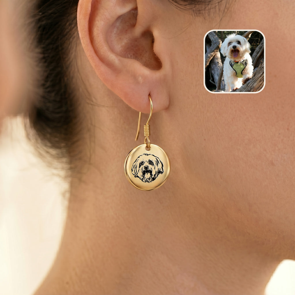 Single gold portrait drop earring worn on one ear, with an inset photo of the white dog it was drawn from
