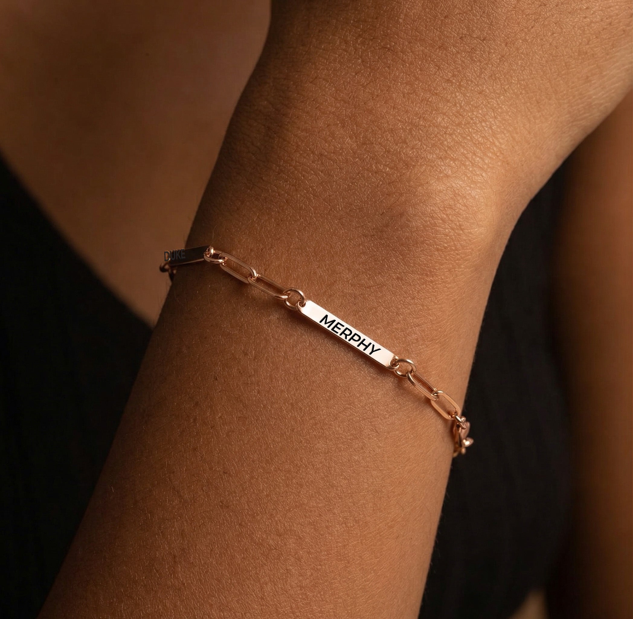 Rose gold paperclip chain pet name bracelet with engraved name bars worn on a wrist