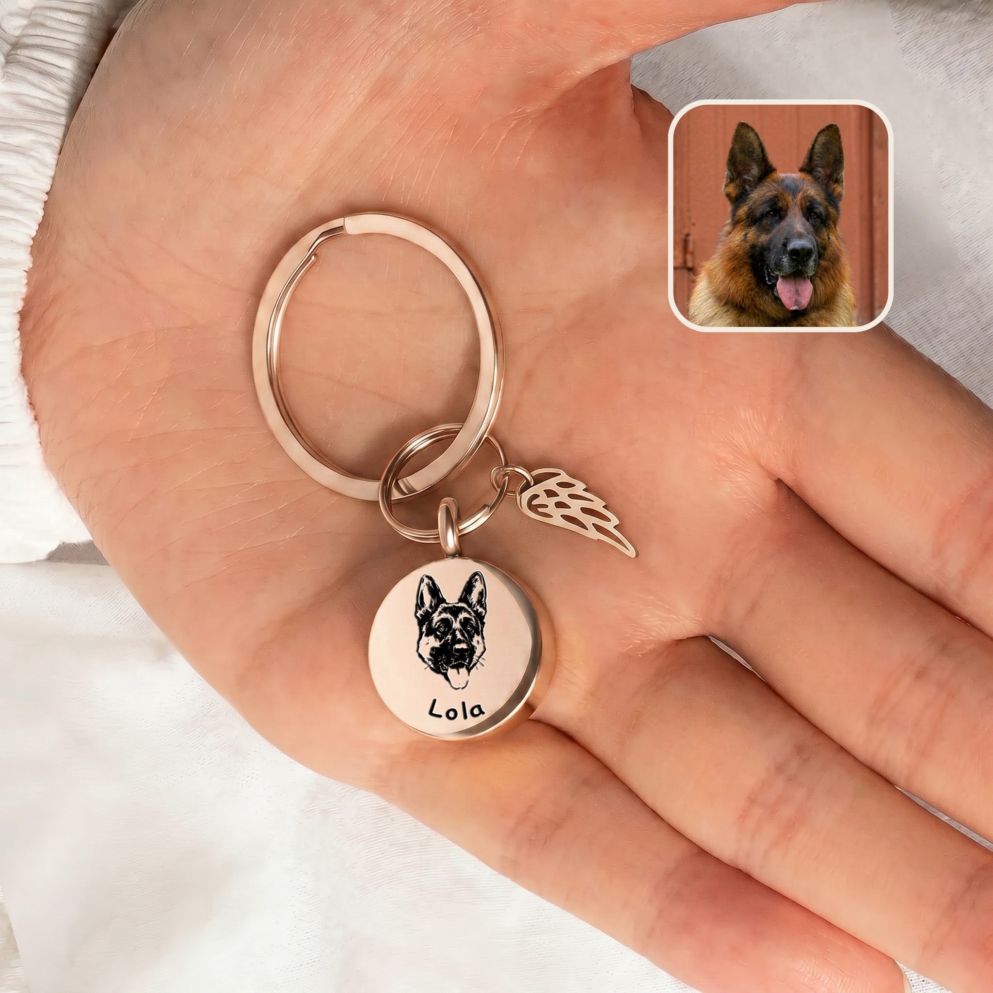 18k rose gold-plated pet cremation disc keychain with angel-wing memorial charm shown in an open hand beside a reference dog photo inset, scale-only no in-use carry