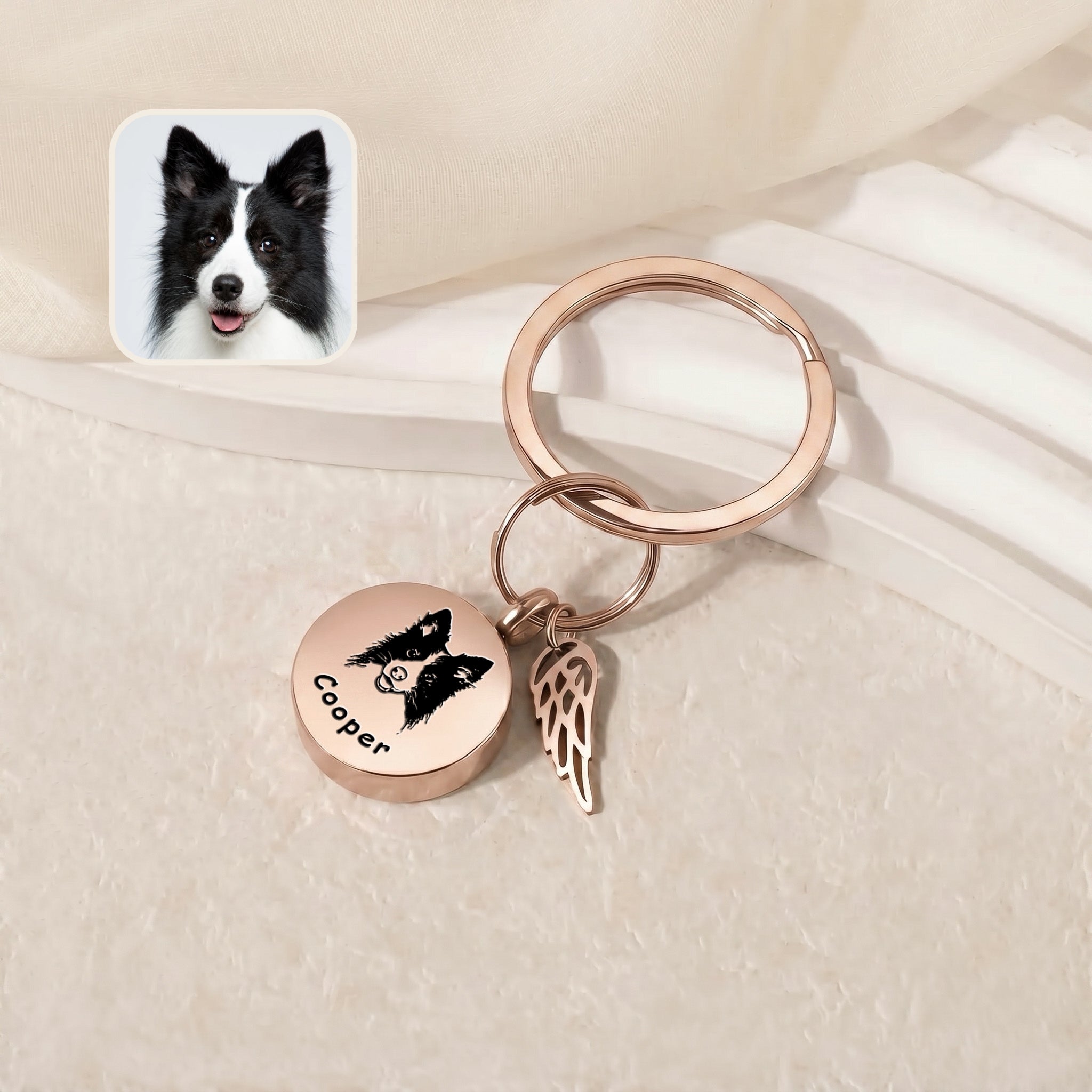 18k rose gold-plated pet cremation disc keychain &mdash; engraved disc and angel-wing memorial charm on a pale stepped tray beside a black-and-white reference pet photo inset