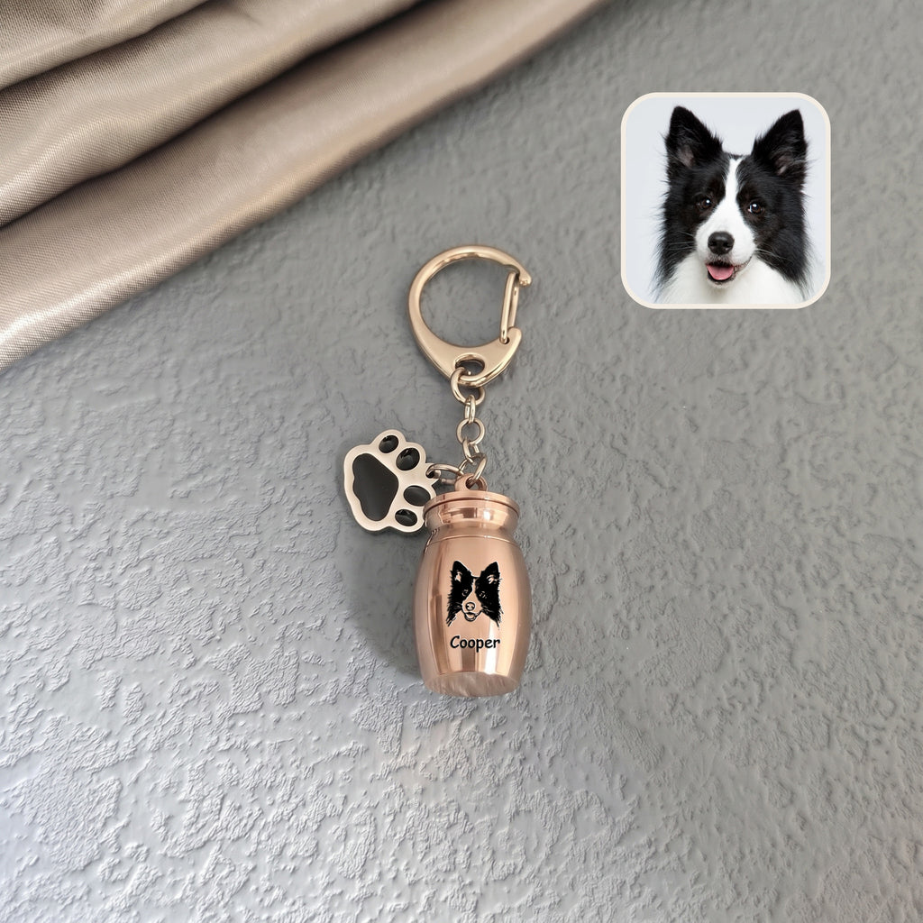 18k rose gold pet urn keychain staged against a textured wall background with a dog reference photo inset, hand-drawn portrait engraved on the capsule face