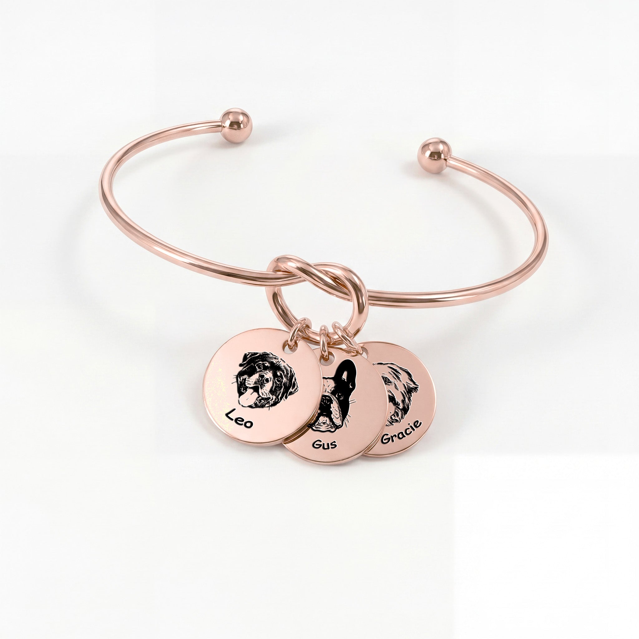 Rose gold knot cuff bracelet with three engraved pet portrait disc charms on a white background