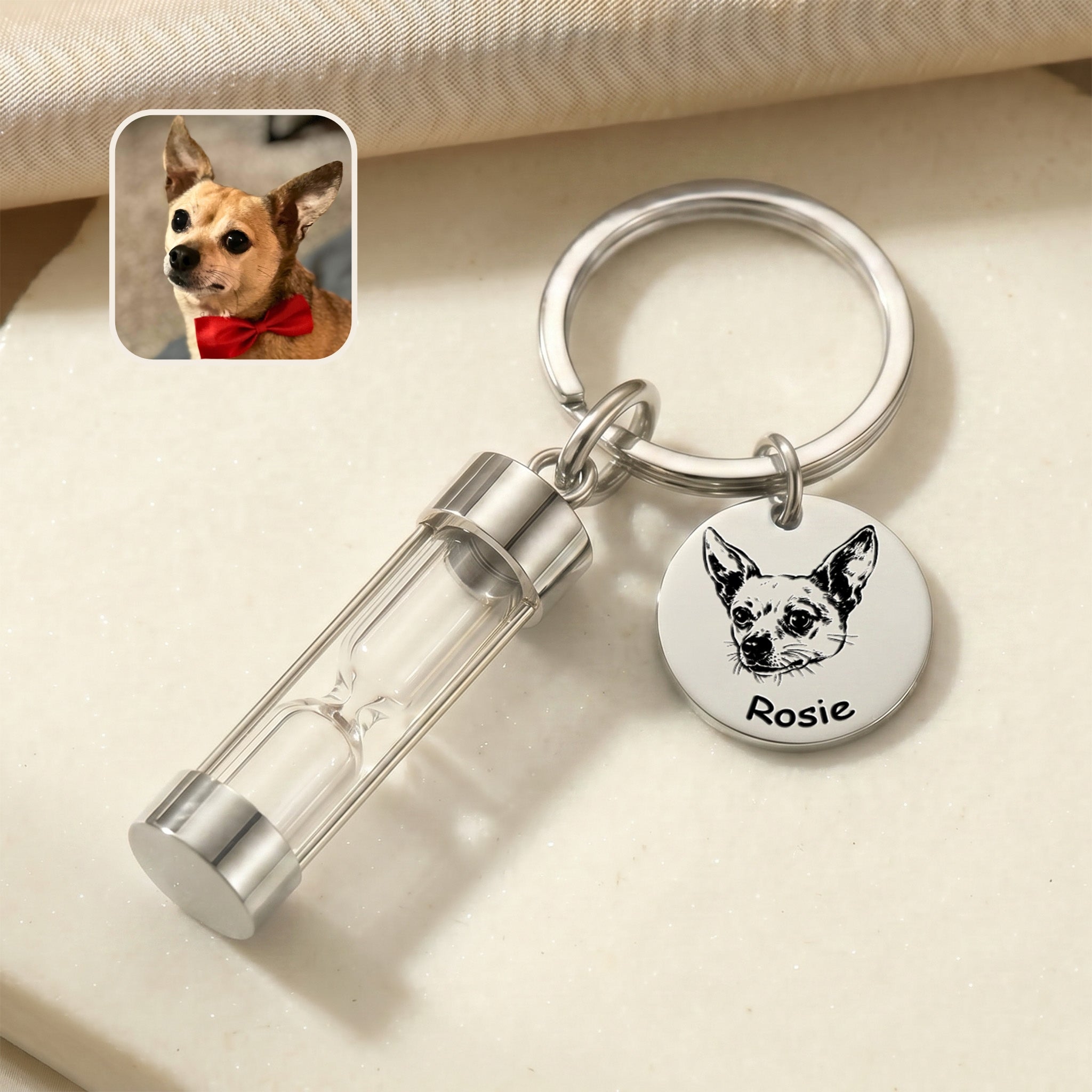 Rhodium-plated pet portrait hourglass keychain on marble surface with engraved chihuahua portrait disc and glass hourglass urn, with reference photo inset
