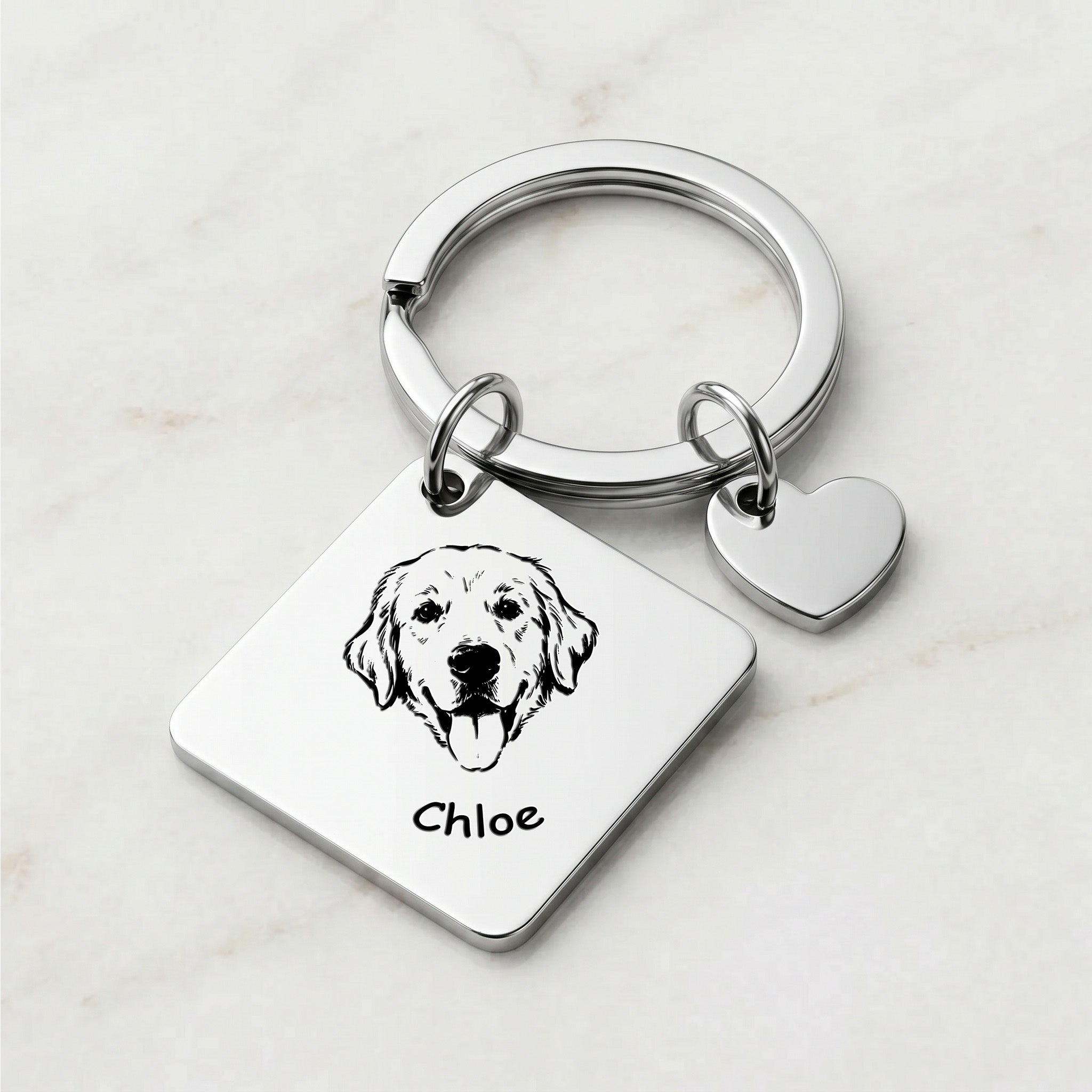 Rhodium pet portrait square keychain on marble surface with hand-drawn portrait and pet name engraved on the front