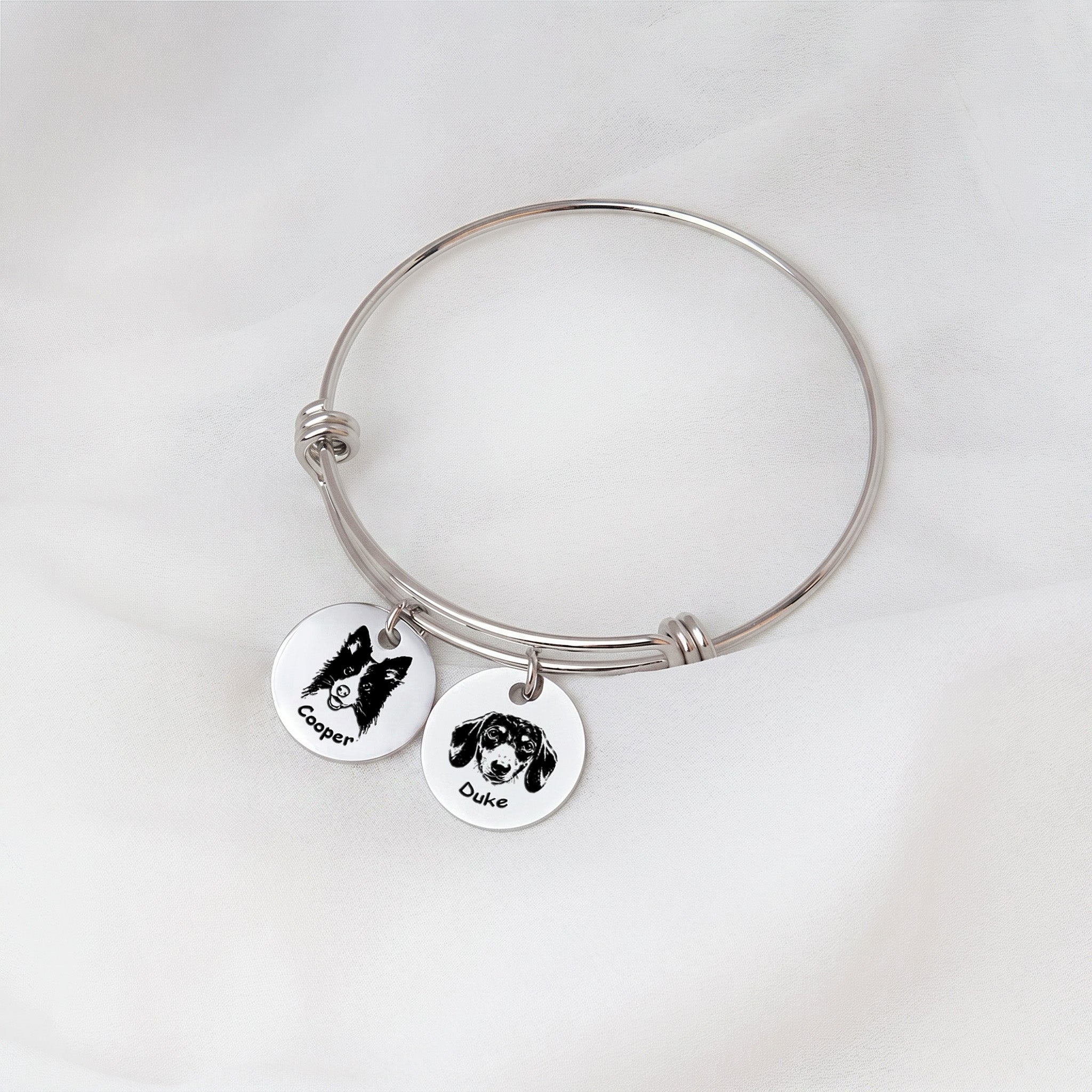 Rhodium silver personalized pet bracelet with two engraved portrait disc charms on white fabric