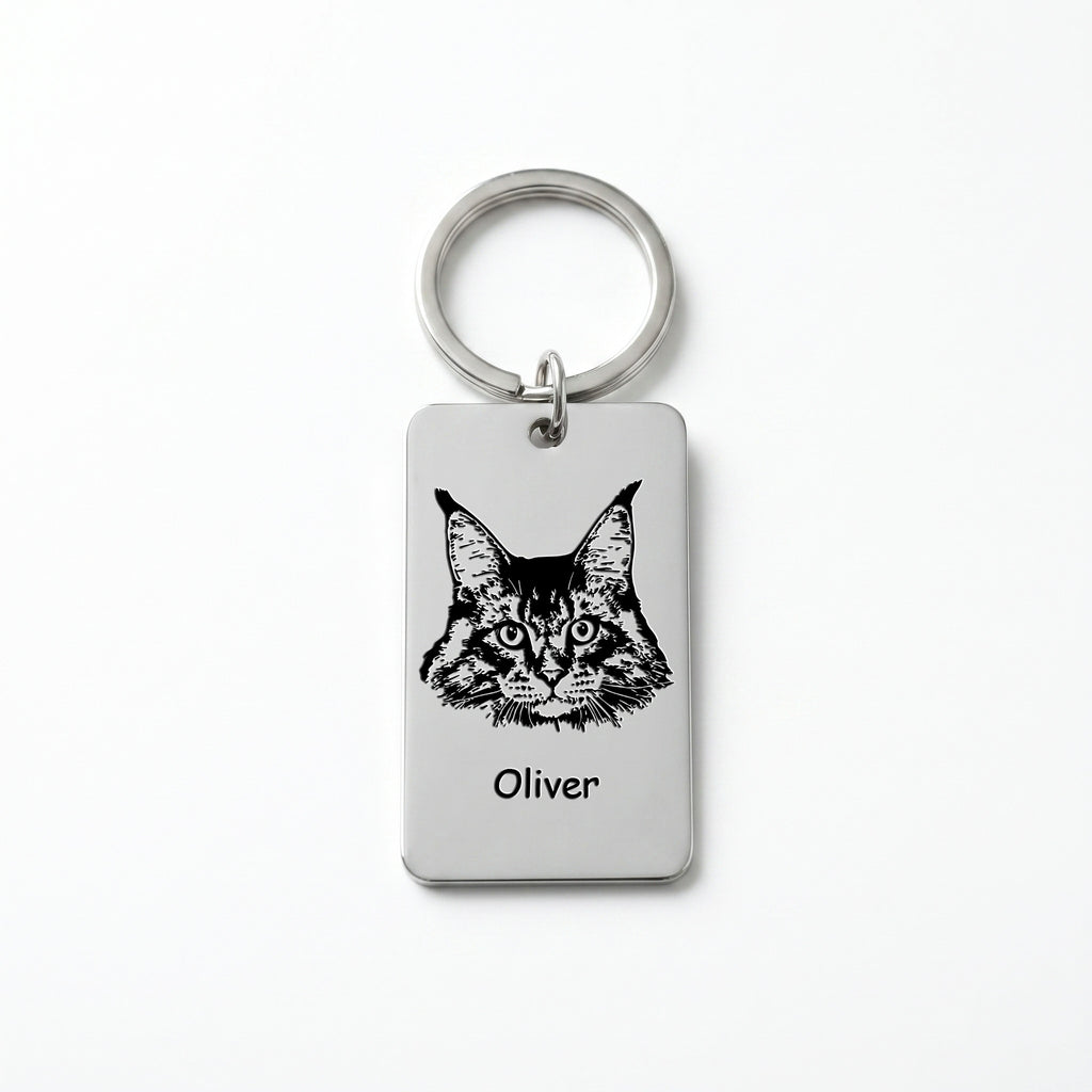 Rhodium pet portrait plate keychain on white background, Maine Coon cat portrait and name 'Oliver' laser-engraved on the rectangular steel plate