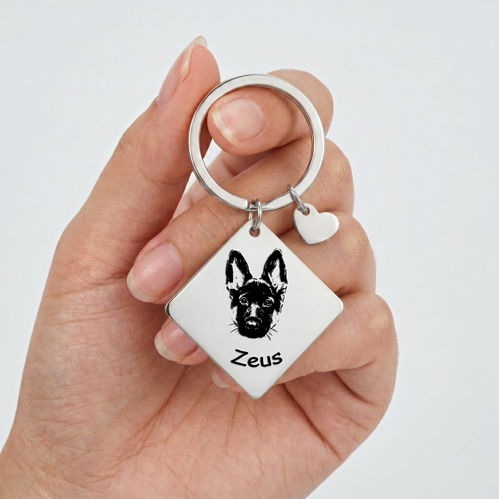Rhodium pet portrait square keychain held in hand showing the square plate and heart charm at scale