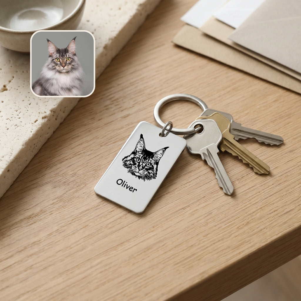 Rhodium pet portrait plate keychain on a wooden desk beside house keys, cat reference photo inset showing the portrait match