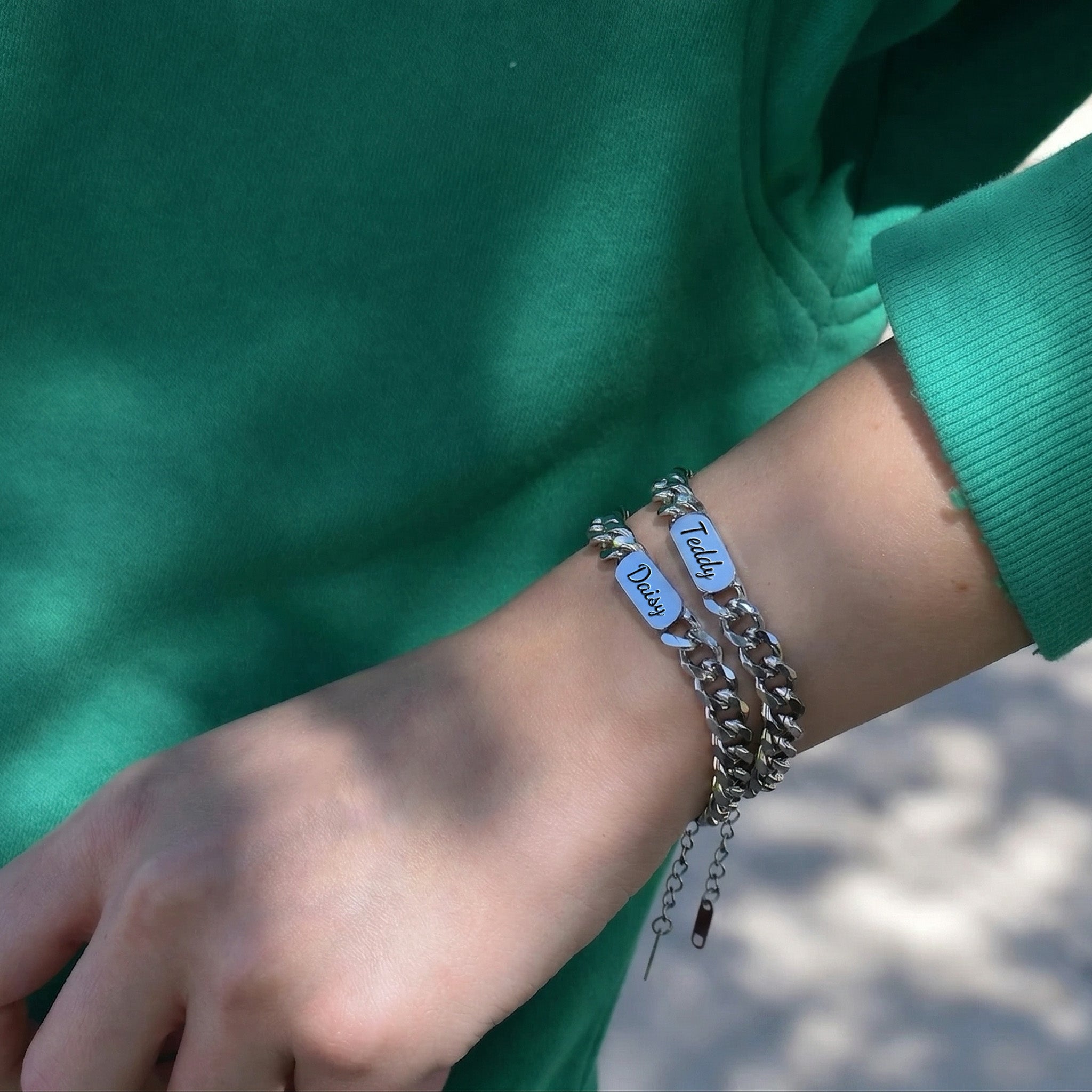 Two rhodium silver pet name bracelets stacked on the wrist, each with a script-engraved nameplate