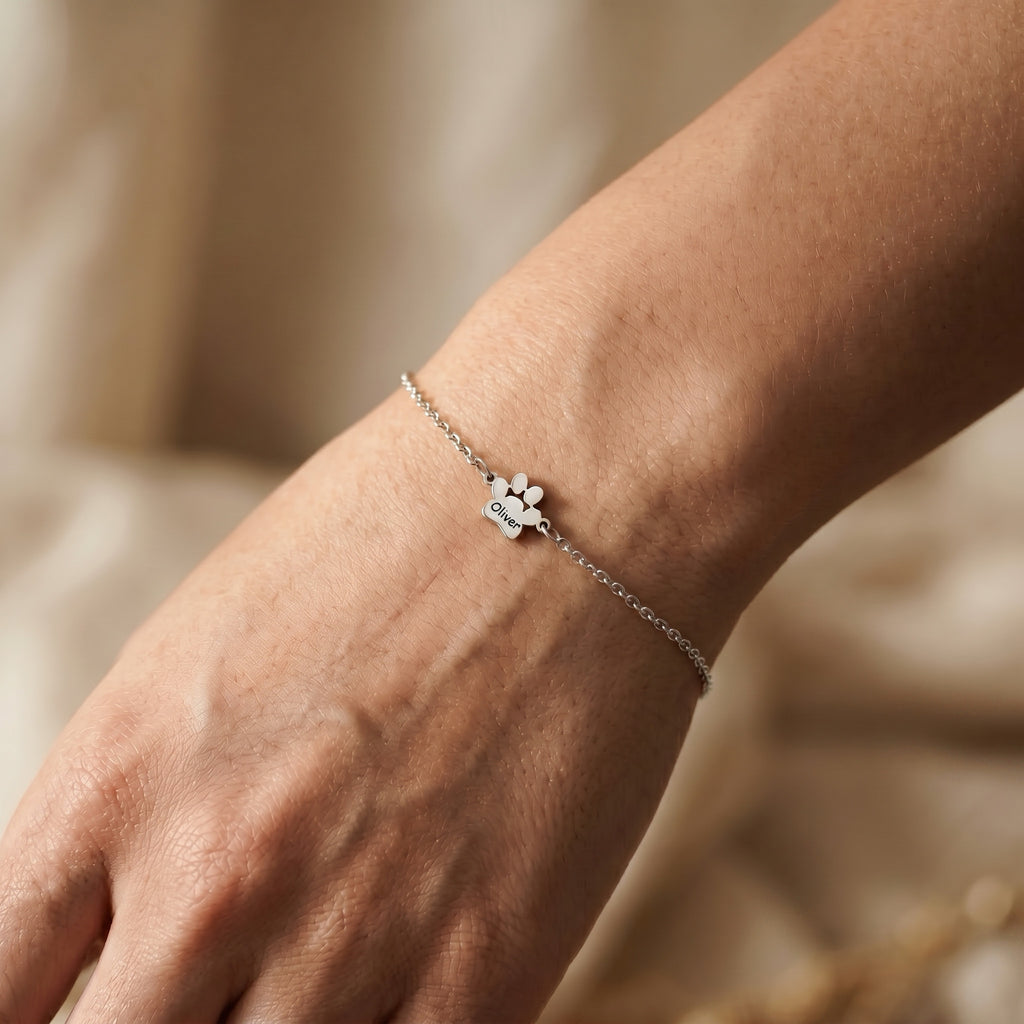 Single rhodium paw charm engraved with a pet name on an adjustable wrist bracelet
