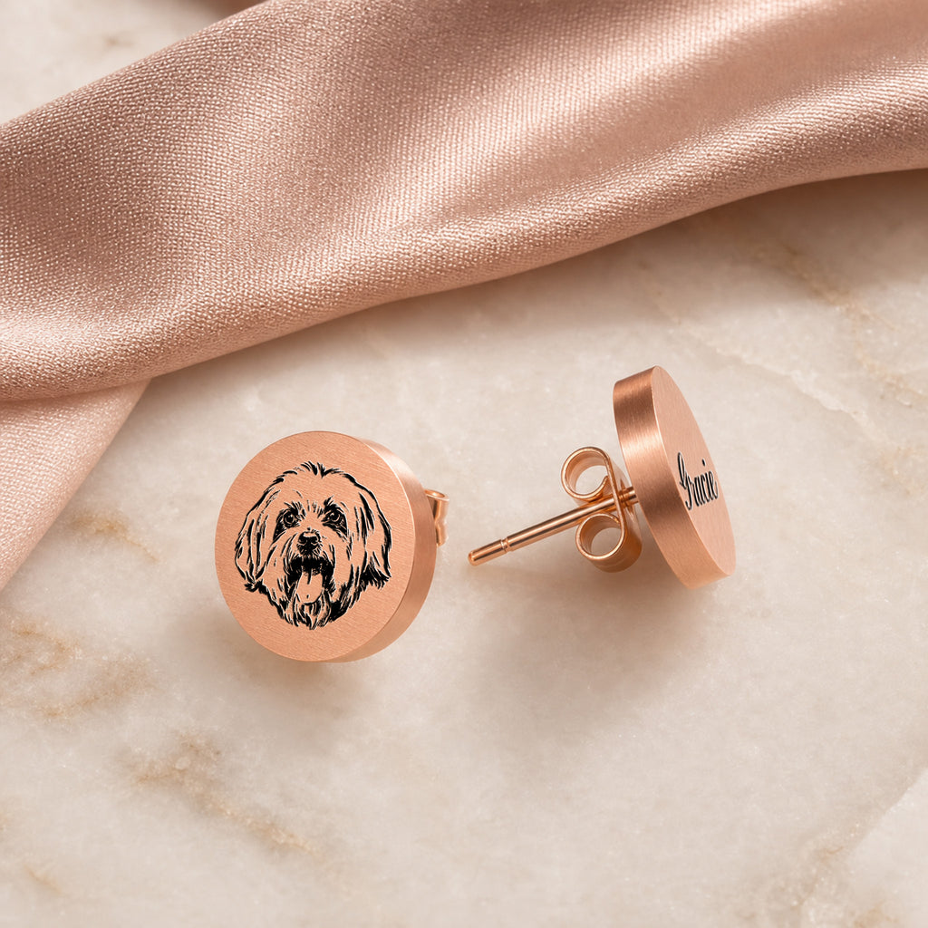 Pair of rose gold pet portrait stud earrings on pale marble, portrait stud and engraved name stud side by side
