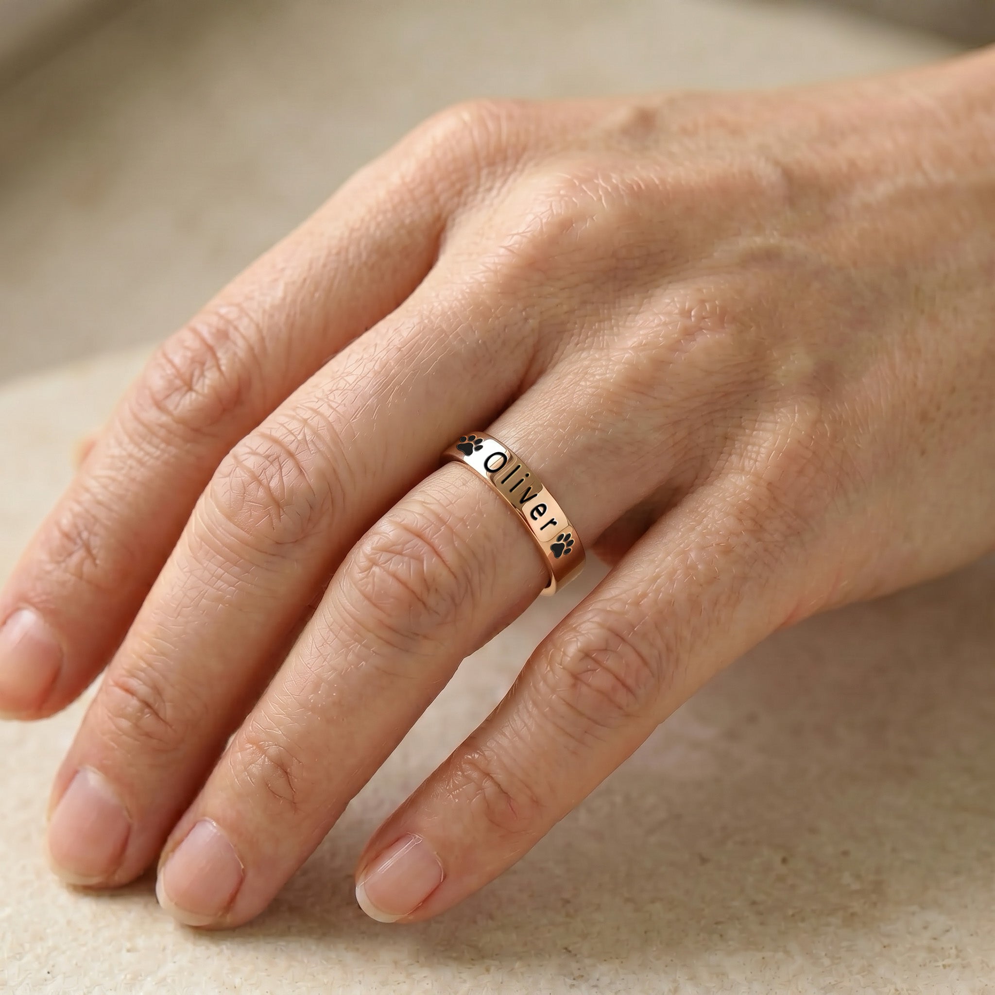 18K rose gold-plated pet name stacking ring worn on a finger in soft natural light