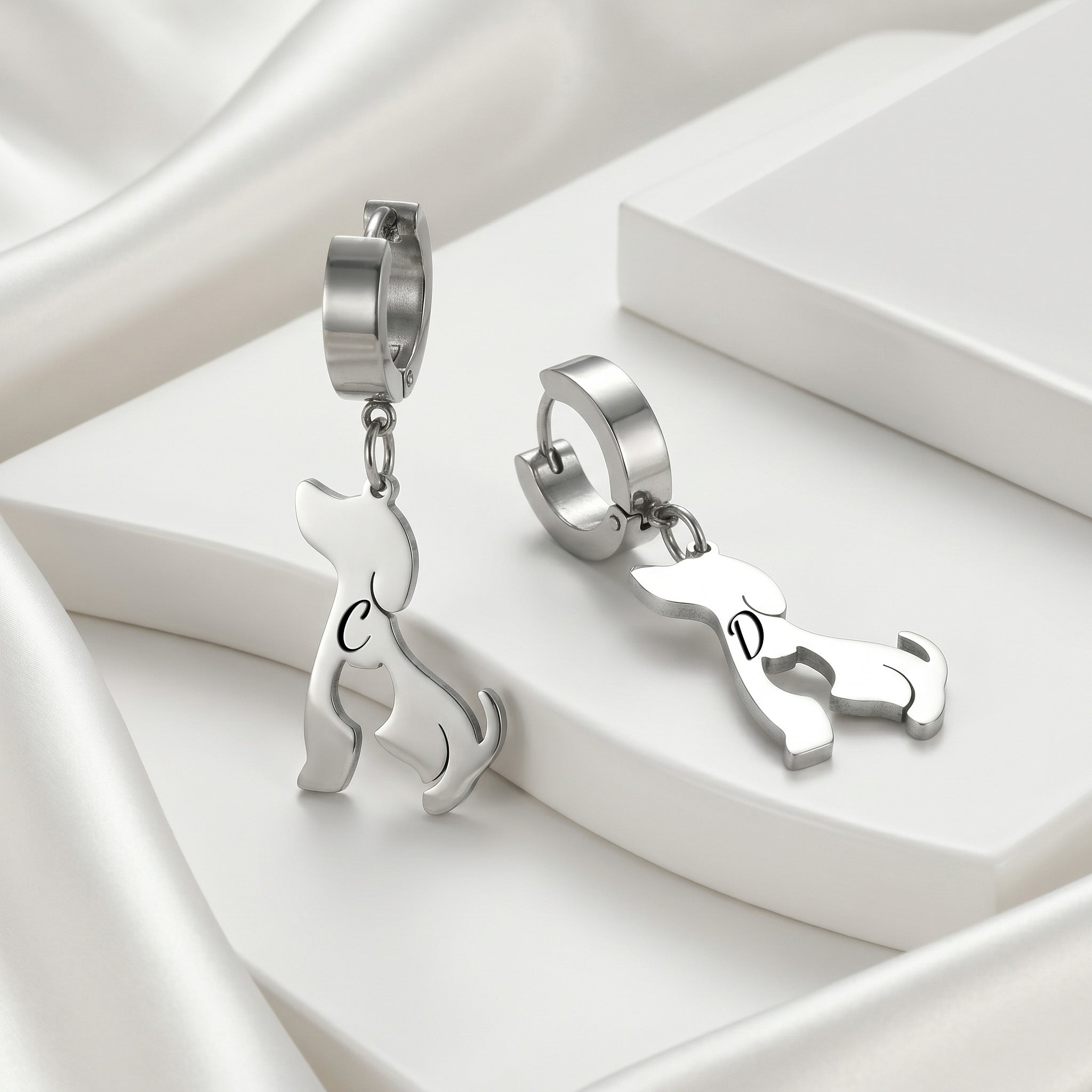 Silver dog-silhouette name earrings displayed on white blocks