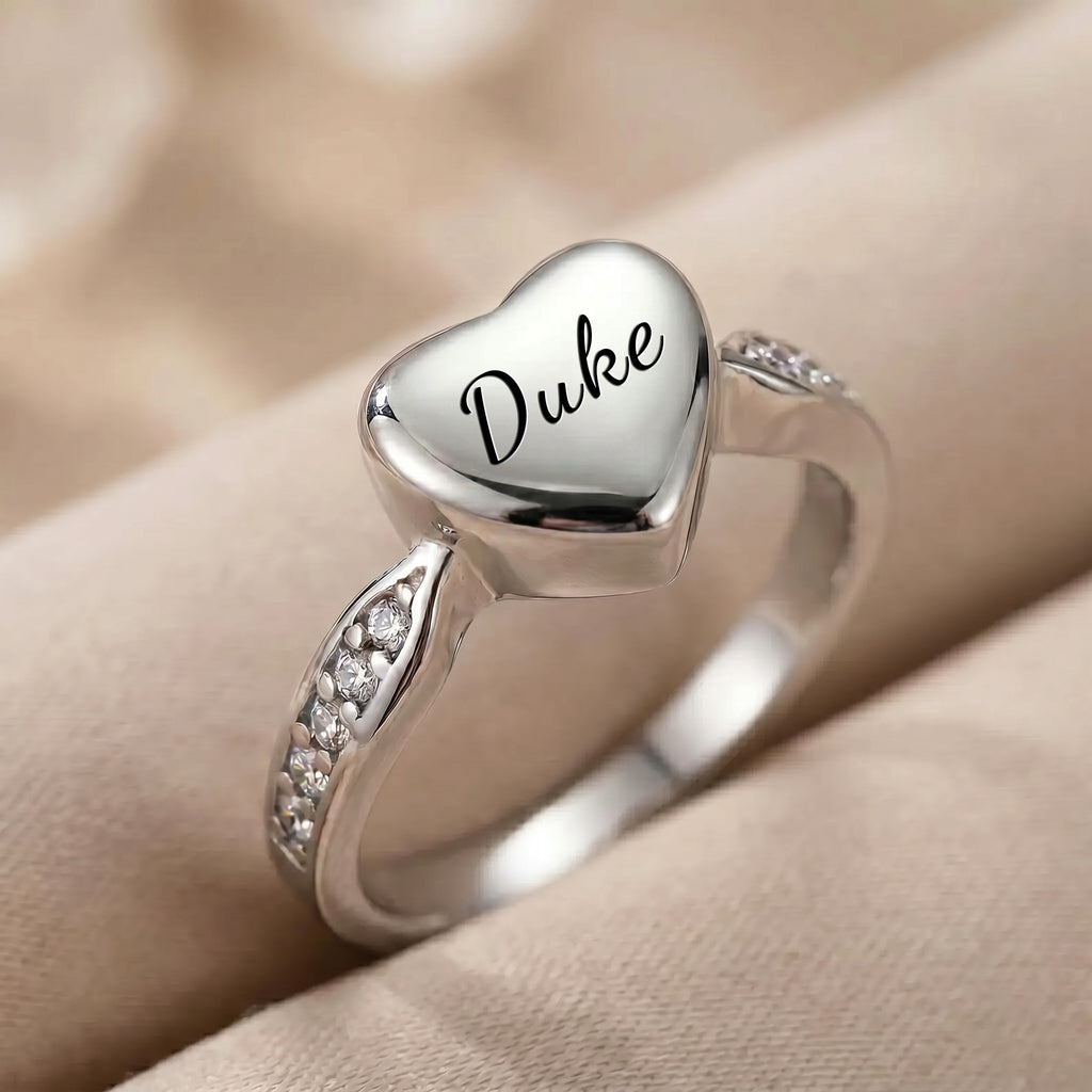 Close-up of silver heart urn ring showing name in script and CZ accent stones set into band