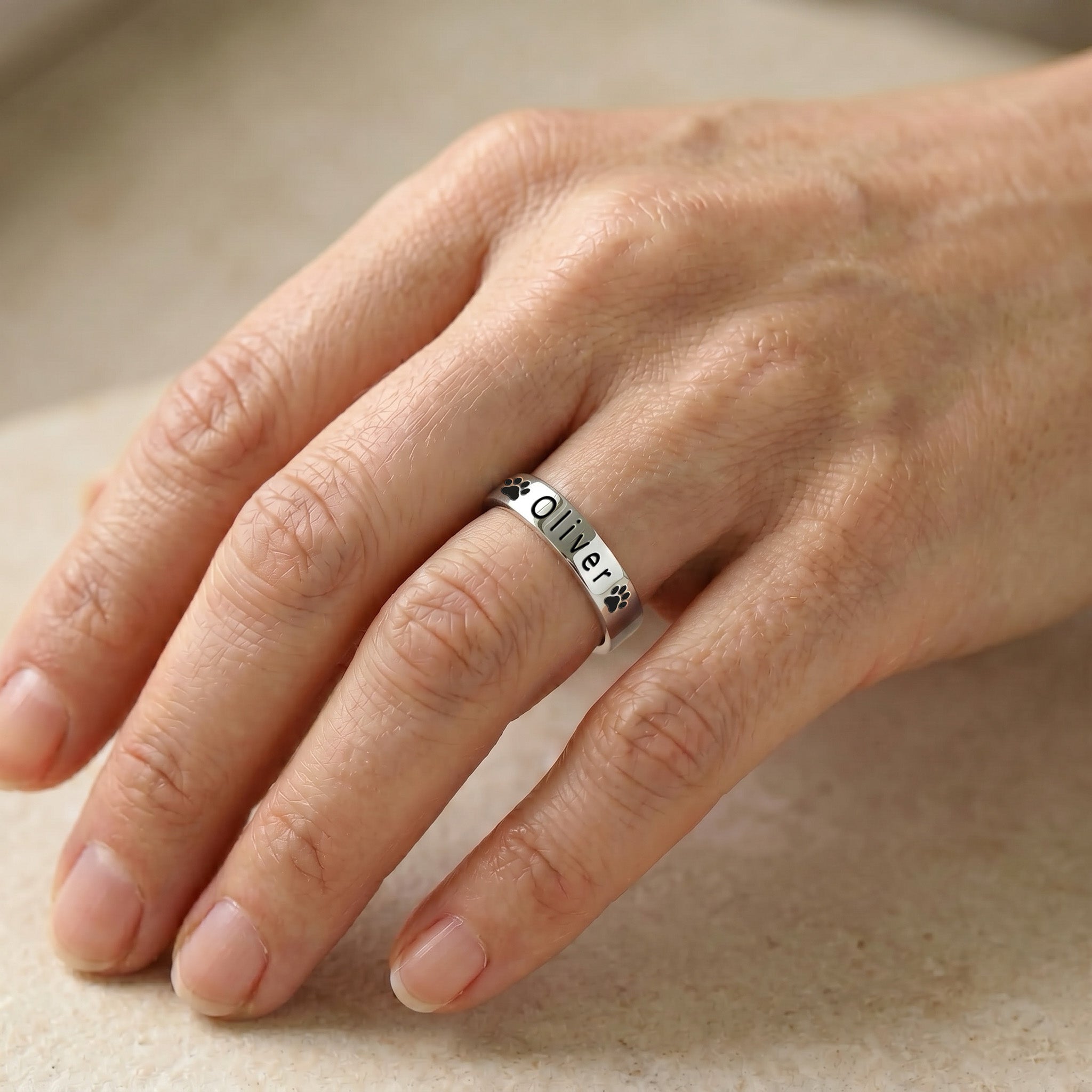 Rhodium-plated pet name stacking ring worn on a finger in natural light