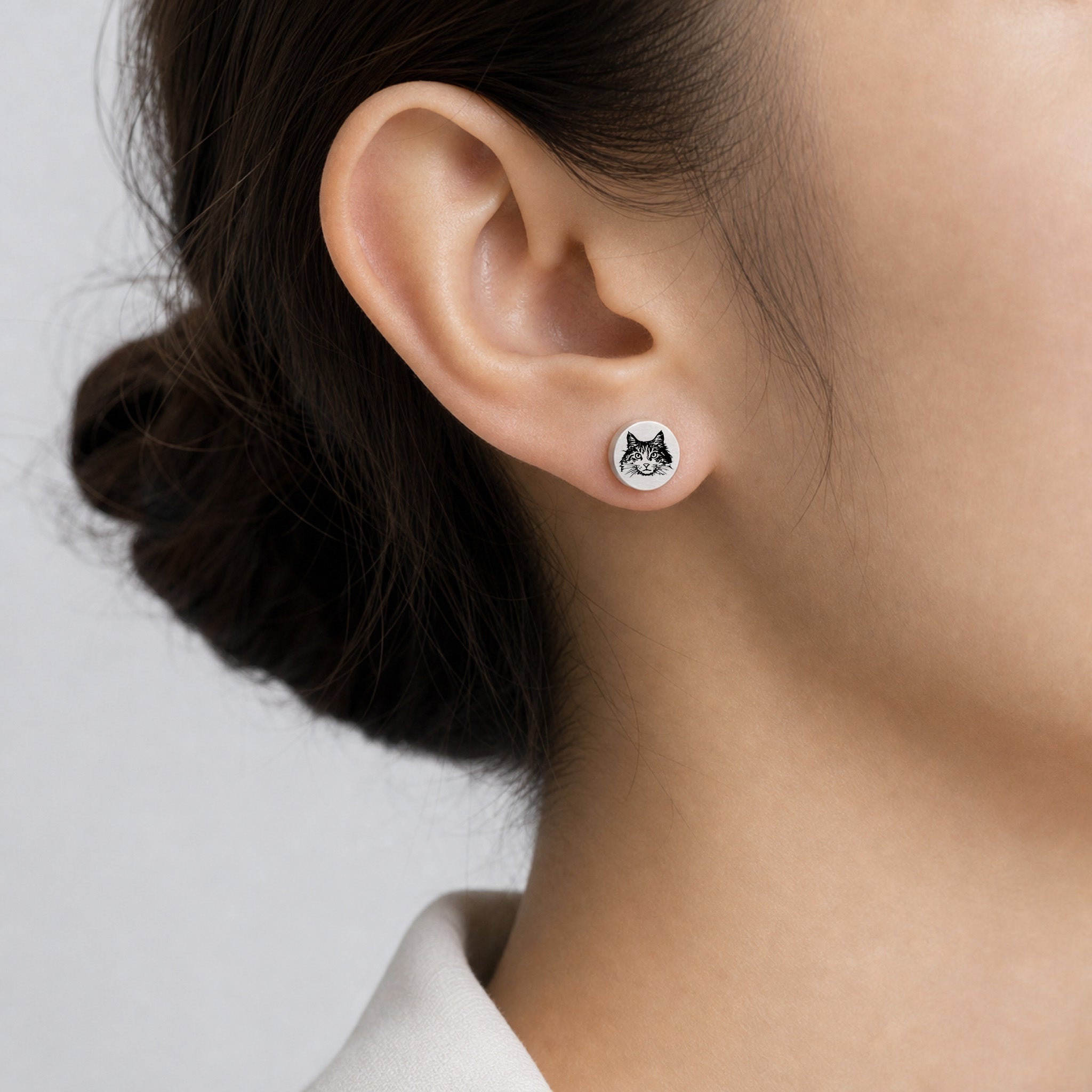 Model wearing a single silver pet portrait stud earring with hand-drawn pet face engraving