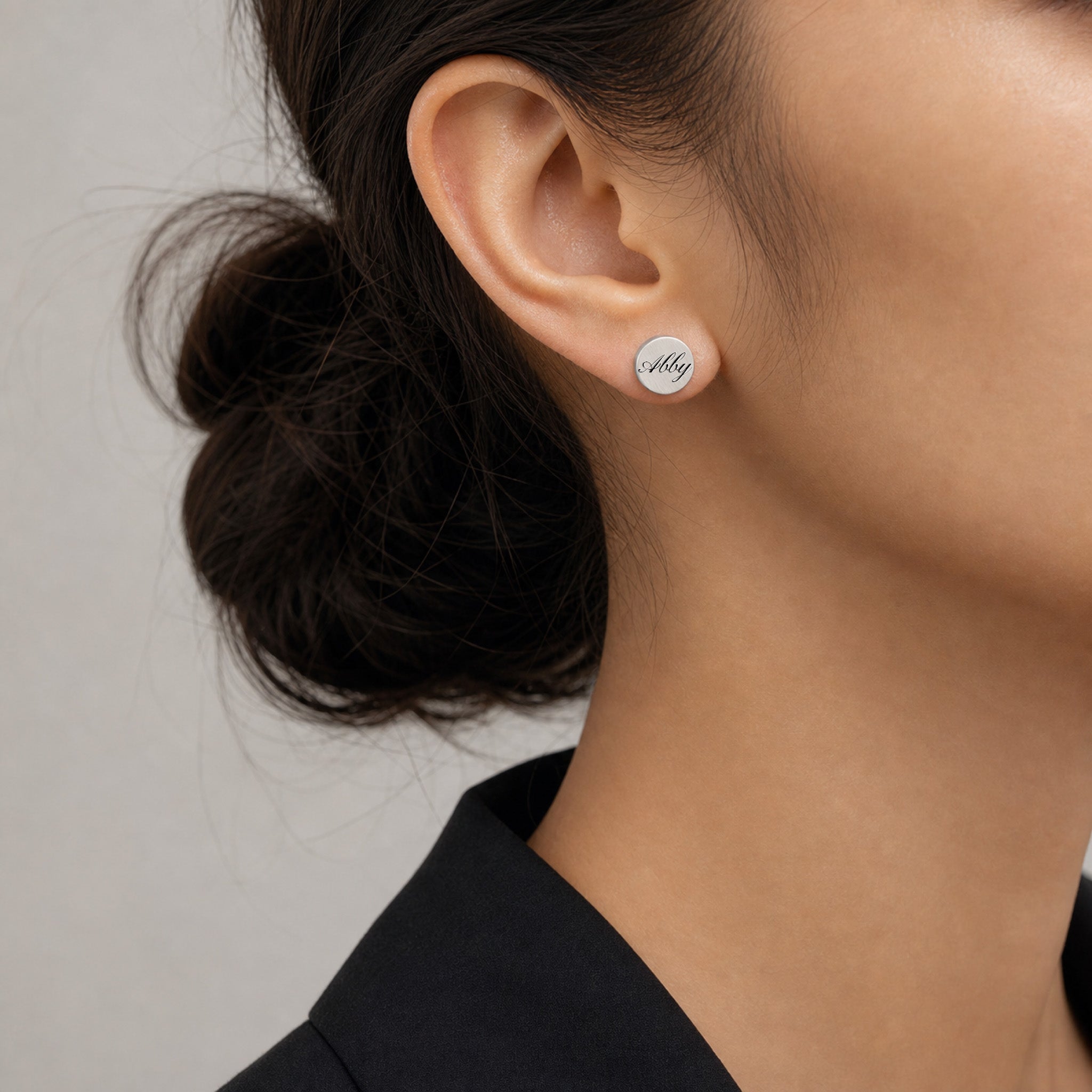 Model wearing a single silver pet name stud earring with script name engraving, close ear view