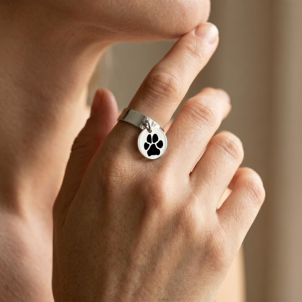Silver-tone disc-charm ring worn on a hand in a soft, warm indoor close-up
