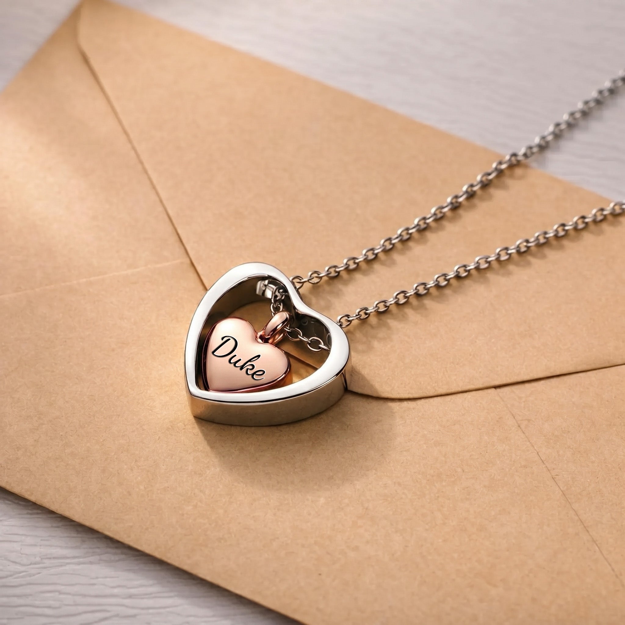 18k rose gold heart urn cremation necklace on kraft envelope, name engraved on inner heart pendant