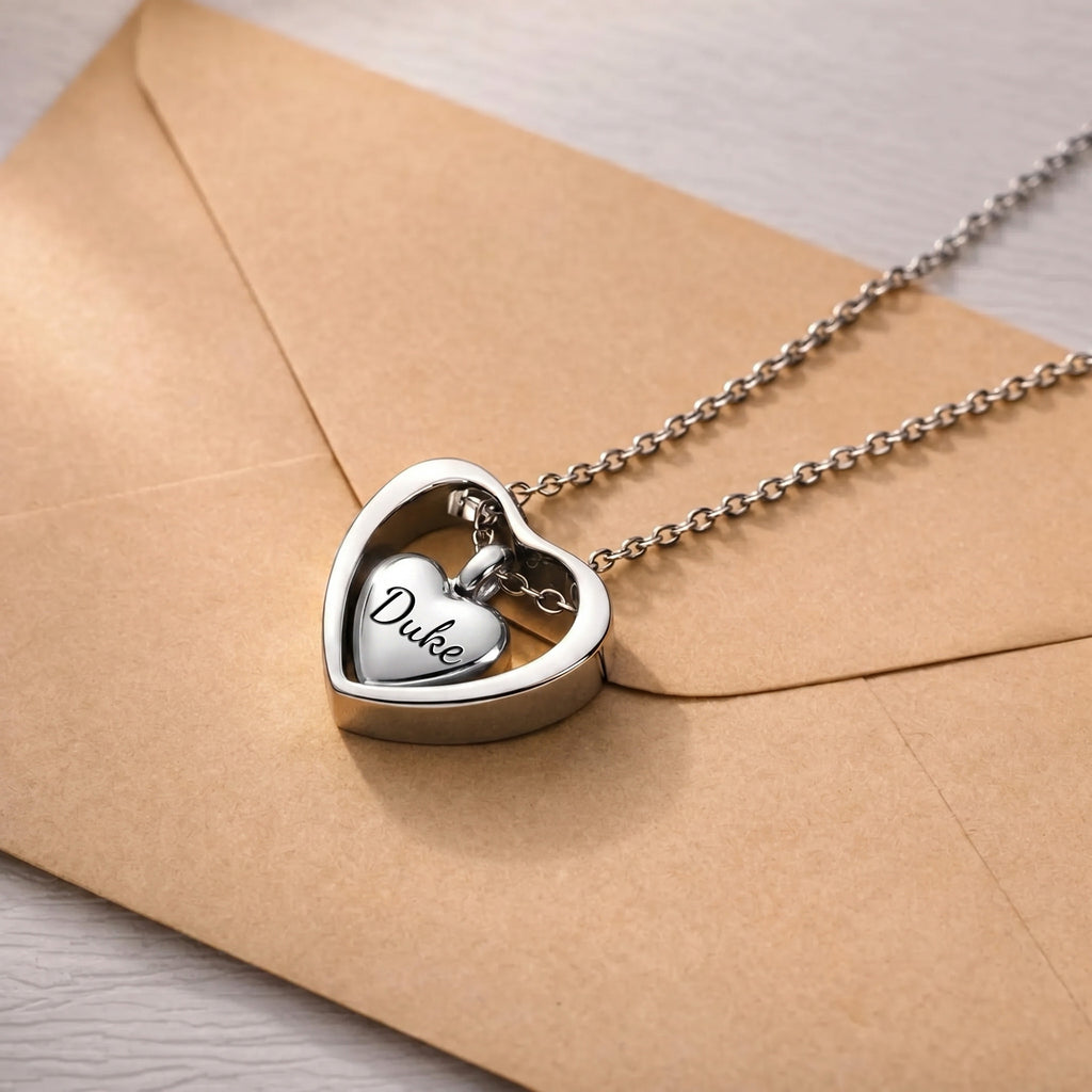 Rhodium heart urn cremation necklace on kraft envelope, name engraved on inner heart pendant