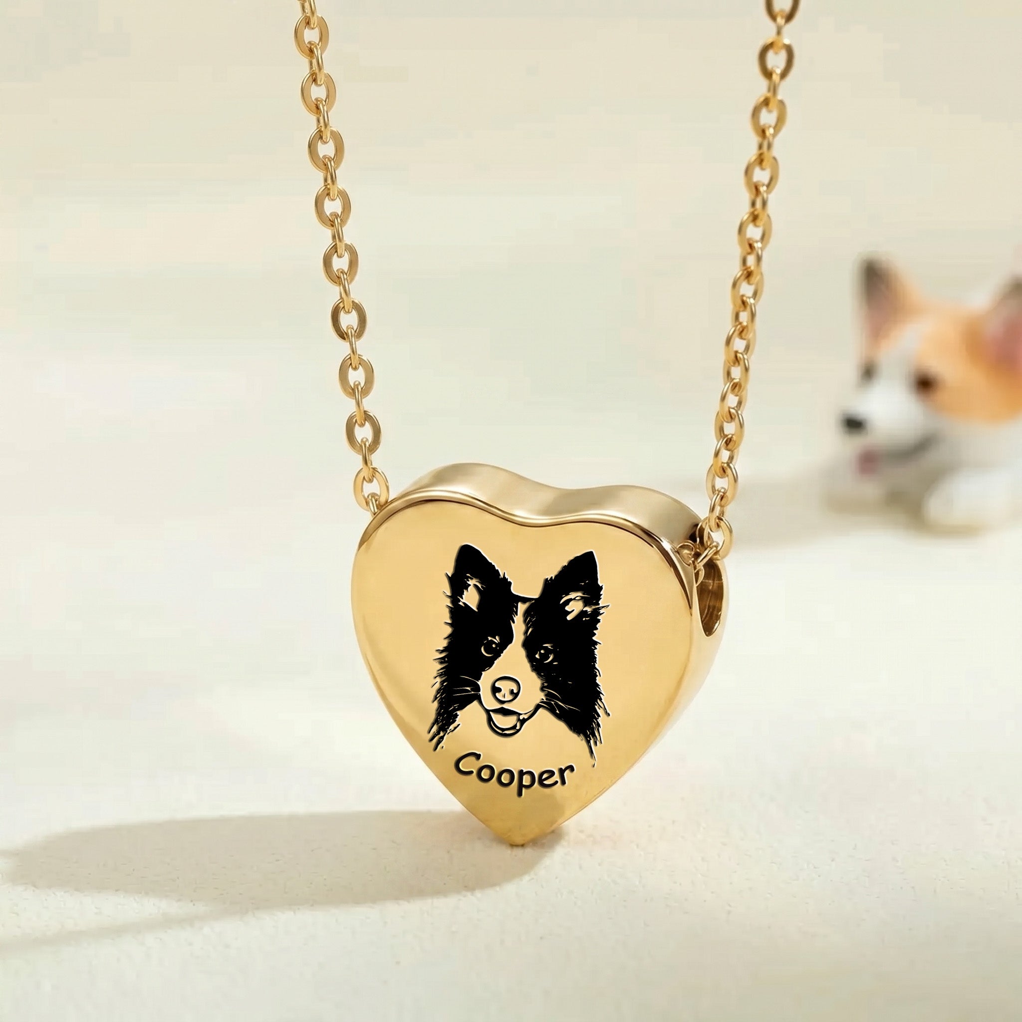 18k gold pet photo heart urn necklace close-up showing hand-drawn portrait engraving with blurred corgi in background