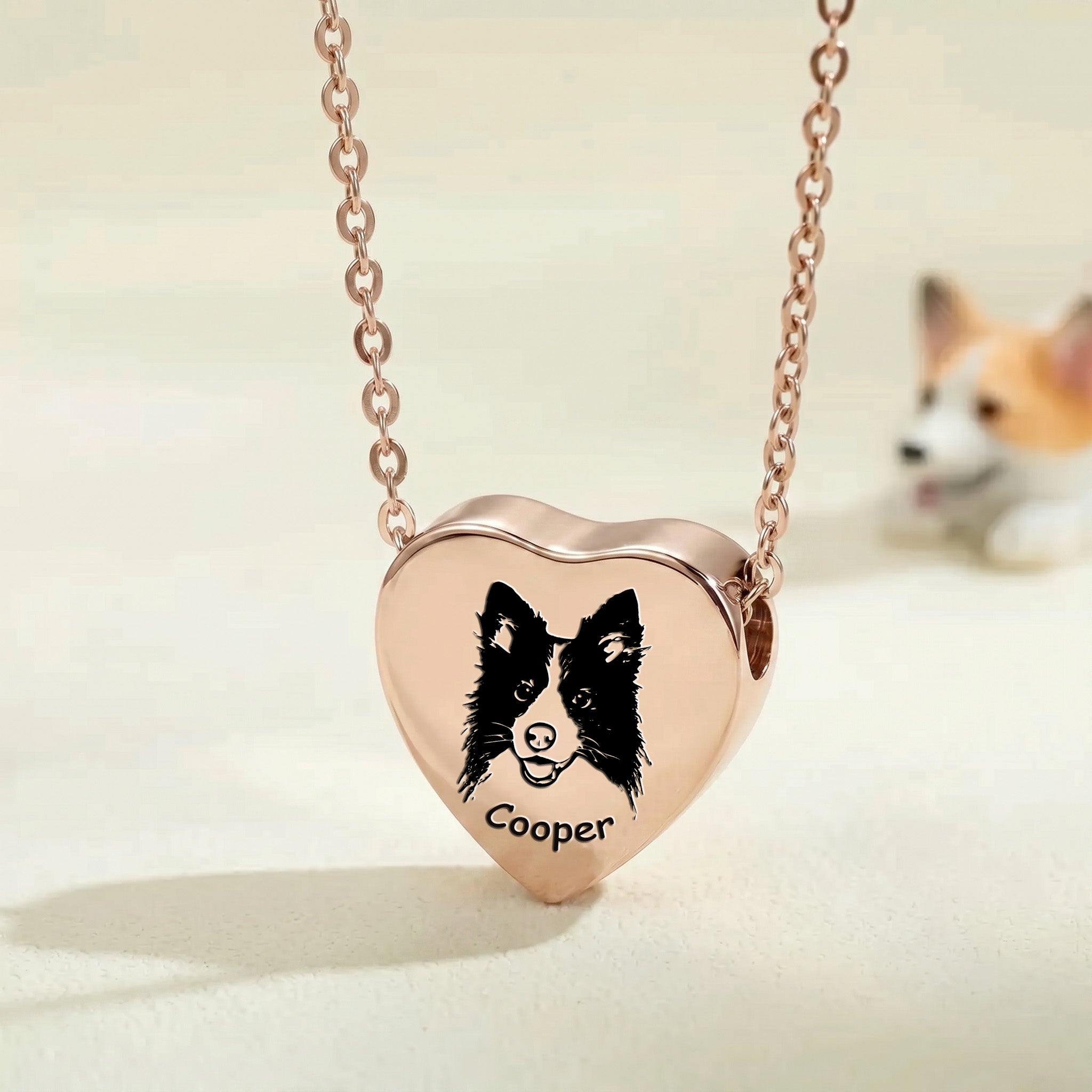 18k rose gold pet photo heart urn necklace close-up showing hand-drawn portrait engraving with blurred corgi in background